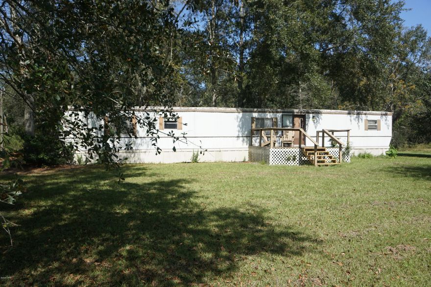 PROPERTY UNDER CONTRACT; SELLER ACCEPTING BACK UP OFFERS. 2 bedroom, 2 bathroom split bedroom home with an extra room that could be used as a 3rd bedroom (no enclosed closet space) or office. Open living room and dining room. Inside laundry hook ups off from the kitchen and a large covered back deck.  The property has an outbuilding with lean to space and an enclosed area all on 3.4+/- acres just North of Chipley, Florida. Enjoy the peace of the country only a few minutes drive from town. Home conveys with a stove and refrigerator and window units. Land has frontage on Wolfbay Rd and Enfinger Road