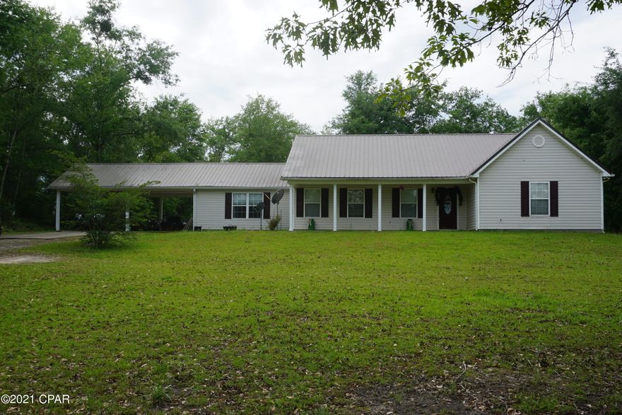 Just bring your rocking chair and enjoy quiet, country living! This spacious home offers five bedrooms (a rarity!) and three bathrooms, perfect for a large or expanding family. Nestled on seven acres in Sneads, Florida, the heart of this property is the beautiful 3000 square foot home featuring newer metal roof and solid core vinyl plank flooring (both less than three years old).  The home is climate controlled with two separate HVAC systems (~7 years old and ~3 years old). There is fresh paint and new lighting in the common areas of the home. Kitchen features a large farmhouse style sink and granite countertops.  Cabinets have been recently painted and appliances are stainless steel. Primary bedroom features a large bathroom with tiled shower and jacuzzi tub. The suite also includes a walk-in closet and separate office.  French doors open onto a screened porch overlooking the fenced-in back yard. Three additional bedrooms are located on the opposite side of the house, one of which is another primary suite with private bathroom and walk-in closet.  A third bathroom is situated in the hall between the other two bedrooms.  The home includes a bonus room that can be used as a fifth bedroom, additional office, den, dining area, etc. Connected to the main house is a two-car carport.  Property also features an enclosed barn/shop approximately 36'x32', complete with concrete flooring, running water and electricity, and an additional air-conditioned room, perfect for a shop office or tackle space. Shop includes two roll-up doors and plenty of work and storage space. Much of the seven acres remains wooded and is home to a variety of hardwoods and an abundance of deer. This home has everything you need and more, with space for everyone! (Measurements are estimates and should be verified if important to buyer. Buyers are encouraged to have a pre-qualification letter or proof of funds before scheduling a showing.)
