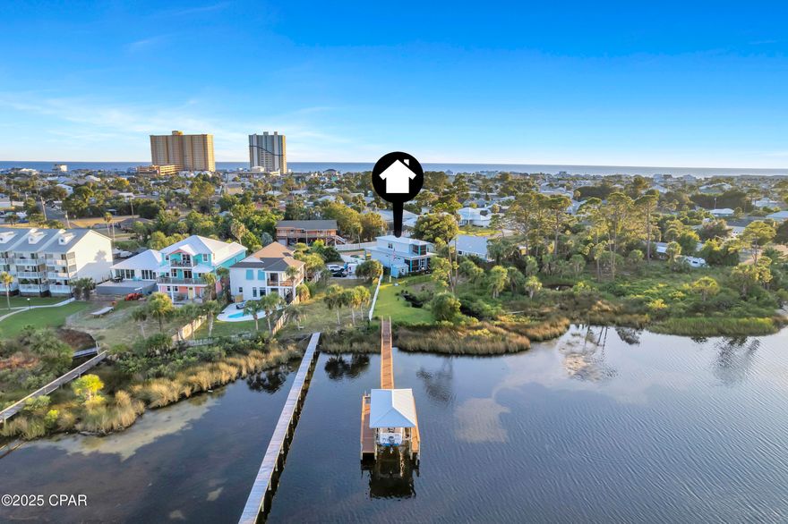 RARE WATERFRONT. LAGOON-MOUTH PROXIMITY. PRIVATE DOCK + LIFT. Set on a quiet loop in Panama City Beach, this property sits in one of the closest residential pockets to the mouth of the lagoon, a scarce location-first opportunity that means quicker runs to open water, marinas, and beaches while keeping a calm, remote feel at home. Out back, a private dock with powered boat lift makes ''go now'' boating simple; when dinner calls, it's an easy hop by boat across the lagoon to local favorites like Capt. Anderson's or The Grand Marlin, or stay dockside and hook saltwater trout and redfish right from your backyard. Daily scenery includes passing boats and jet skis, ospreys and eagles overhead, and dolphins that make regular rounds. On the 4th of July, watch large-scale fireworks lift just beyond the bridge—visible from the dock and both screened porches. Built with 2x6 construction, hurricane-rated doors and windows, and spray-foam insulation throughout (including interior walls) on pilings driven approximately 47 feet, the home blends efficiency and resilience. Inside, well-appointed living spaces are oriented to the water and flow to a screened-in back porch; upstairs, the primary suite has its own screened porch—another great vantage point to enjoy the amusements of wildlife and watercraft all day long. The result is the rare blend of remote feel and minutes-to-everything convenience, exactly where you want to be when waterfront access matters most. All information is believed accurate but not guaranteed; buyer to verify if important.