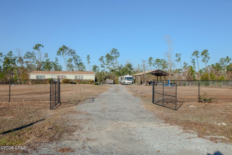 Fully fenced 2.5± acre property featuring a 3-bedroom, 2-bath home with approximately 1,500 sq ft of living space, multiple pole barns, and extensive cleared, usable land. The property includes two large pole barns offering covered parking, storage, or recreational use, making it ideal for buyers seeking space, flexibility, and privacy.

The home offers one of the most functional floor plans you'll find in this style, with a spacious primary bedroom and private bath, along with well-sized secondary bedrooms that each include ample closet space. The open living area provides multiple layout options, including room for both living and dining areas.

The kitchen is generously sized with abundant cabinetry, countertop space, a pantry, and a dedicated dining area, making it well-suited for everyday living. Interior and exterior single-pane windows provide added insulation typical for this construction style.

Significant foundation updates have been completed, including replacement tie-downs and proper securing of the home, offering peace of mind to future owners. The property is located in an area with similarly sized acreage homes, providing a sense of space while maintaining a neighborhood setting.

This is a rare opportunity to own a solid, well-laid-out home on fully fenced acreage with substantial outbuildings -- ideal for buyers needing land, storage, or room to spread out.