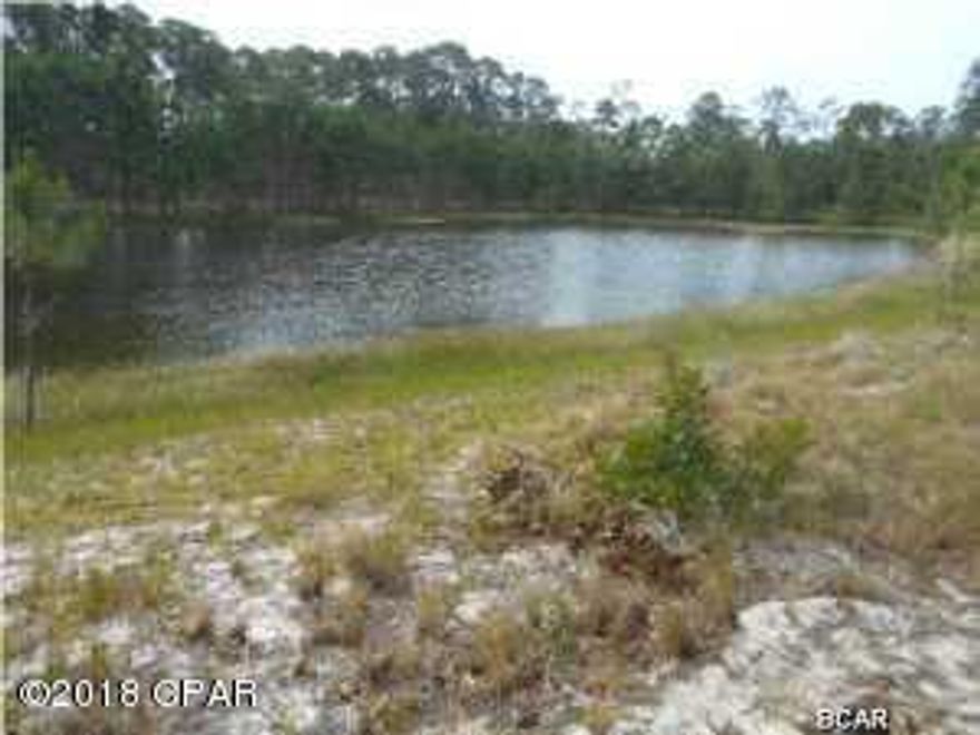 Almost an acre on scenic pond at Wild Heron, which is an exclusive subdivision on Lake Powell, the largest coastal dune lake in North America with Shark's Tooth Golf Course designed by Greg Norman; enjoy the large pool with hot tub,community room, fully equipped fitness center viewing Lake Powell, dock, trails, and tennis courts. There is a boathouse with canoes/kayaks and deck with stone fireplace and tables for dining. It is prestigious, and residents love being able to walk around on the quiet community streets. The beautiful pool overlooks picturesque Lake Powell. Just a short ride to Camp Helen State Park, the quiet west end beaches,Seaside, and other villages on 30A, and it is a fifteen minute drive to Pier Park and Frank Brown Sports Park. This is a rare large lot on scenic pond but will not require flood insurance. Build your cottage in the natural enviroment of Wild Heron. . Cdd fee is 2547. per year and a new buyer fee of 150. upon purchase.   Buyer should verify all information. Owner may consider owner finance.