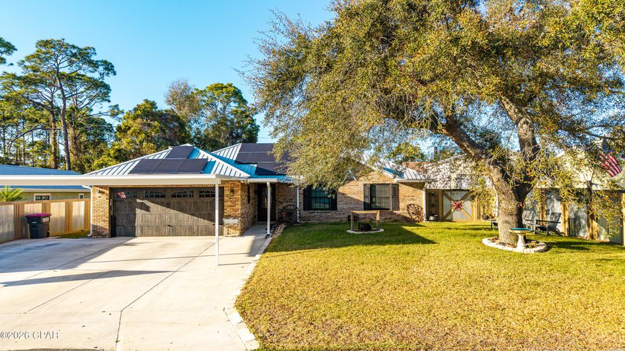 Just off Thomas Drive and directly across from Publix, this beautifully maintained 3-bedroom, 2-bath brick home offers the perfect balance of beach convenience, privacy, and functionality.

Originally built in 1993 and thoughtfully updated since 2017, the home blends solid construction with modern upgrades and distinctive interior craftsmanship. 

Inside you'll find luxury vinyl plank flooring, solid wood interior doors, tongue-and-groove paneling, and craftsman-style trim that create a warm, cohesive feel throughout the home.

The kitchen features Samsung stainless appliances, farmhouse-style touches, and inviting lighting, opening naturally into the dining and living areas where a custom fireplace and rustic wood accents create a comfortable gathering space. 

Each room reflects pride of ownership and intentional design. With 1,756 heated and cooled square feet (2,412 total under roof), the home also offers impressive efficiency thanks to solar panels that have reduced the current owner's electric bill to approximately $30 per month, along with newer windows that enhance comfort year-round.

Outside, the property is built for both practicality and entertaining. An expansive insulated metal panel covered driveway provides space for up to six vehicles in addition to the two-car garage, making it ideal for guests, boats, or multiple vehicles.

The large covered rear porch and outdoor dining area, also built with insulated metal panel roofing, create a shaded and comfortable outdoor living space. Custom sun shades add additional cooling, making it perfect for relaxing or entertaining after a day at the beach.

The backyard has been designed for low-maintenance enjoyment, featuring paved walkways, decorative pebble rock borders, and a stylish custom fence with wood framing and corrugated metal panels. A large side gate provides access for equipment or a tractor and leads to a dedicated workshop/storage area with pegboard walls, plus an additional covered lean-to for tools and lawn equipment.

And for buyers who fall in love with the style, much of the home's furniture and décor is negotiable, offering the opportunity to purchase the home nearly turnkey.

Located just minutes from the beach, dining, and shopping, this solid brick home combines location, character, energy efficiency, and exceptional parking