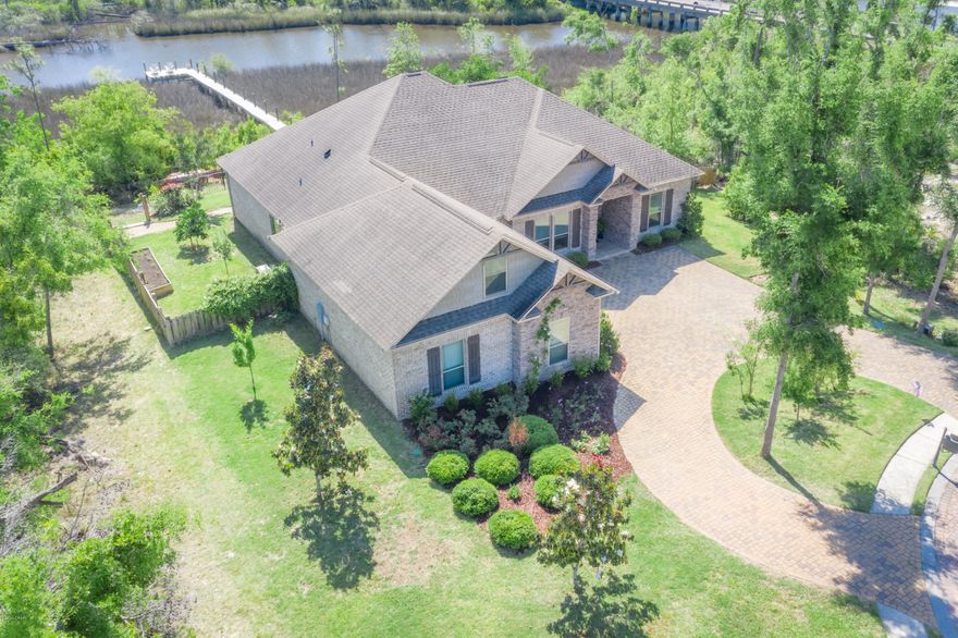 WATERFRONT BEAUTY IN A GATED COMMUNITY!!! This custom built home is located in the highly desirable Grant Mills II subdivision.  All the extras & attention to detail are sure to spoil your family.  Stunning waterfront views & an open floor plan are two of the most outstanding features that make this home so appealing.  No expense was spared as the home boasts 10' ceilings with crown molding, porcelain tile floors, granite countertops, stainless appliances, custom cabinetry, dining area with an 11' trey ceiling, relaxing & spacious living area with 12' trey ceiling, electric fireplace, new carpeting & smart home capabilities added.  The outdoor screened in back porch provides the perfect place to entertain, & the patio just off the porch offers a perfect location to grill & enjoy the view. The spacious Master En-Suite offers a private luxurious retreat and features a stepped up tray ceiling, a large tiled master bath with custom cabinets, granite counters with double vanities, garden tub and a large walk-in closet. Access from the Master Suite to the porch allows a relaxing waterfront escape to wind down for the night.  The 2nd and 3rd Bedrooms are porcelain tiled with large closets and a hall bath.  The upstairs bonus room is  counted as the 4th bedroom but can be utilized as an office, game-room or theater room room. The spacious laundry room has built in cabinets.  Fresh paint throughout make this home airy and bright and the uplighting on the outside of the home, dock and landscaping makes for a beautiful night view. The bayou has navigable waters leading to the open bay and gulf so bring your boat, kayaks, and jet skis.  The 110' dock features MasterDeck decay resistant wood.  Beautifully landscaped yards are accented with an abundance of fruit trees and an additional parcel of land at water's edge makes this property valuable and unique. To make this home and neighborhood even more appealing, the streets and driveways are adorned with brick pavers.  Home is energy efficient and has a low maintenance exterior. All sizes, including sq. ft. are approx. Please verify if important.  There is a 1% buyers fee.  Don't let this home pass you by!