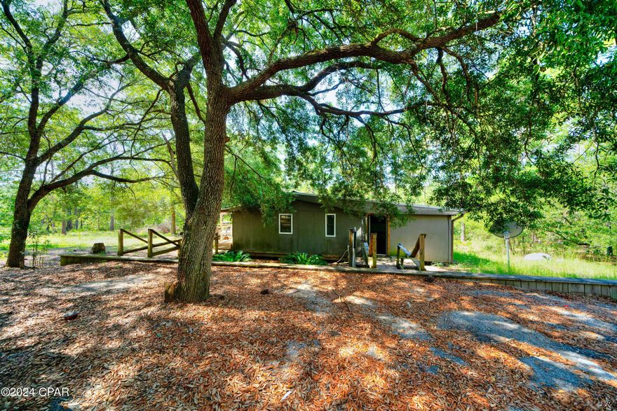OUTDOORSMAN'S PARADISE! If you like to hike, horseback ride or ATV, come and explore nature on this 10.81 acre tract covered with hardwood trees! If you love the outdoors, this could be the place for you. Secluded in South Washington County woods, this distressed structure has great bones and is waiting for some TLC to bring this Outdoorsman's paradise back to life!!!  Surrounded by beautiful woodlands and just a short drive to Panama City, Panama City Beach and Chipley, Florida, and an INTERNATIONAL AIRPORT. This structure features 4 bedrooms, three baths, a wood burning fireplace, living room, great room, open kitchen, two master bedrooms,  and wood beams with a tin roof. Partially gutted, renovations were halted in 2022, and requires additional construction, so this is a blank canvas for the right buyer who has a vision for a space of your own in the woods! Improvements included with this property is a 30 X 30, 5 year old metal garage/workshop with a 30 foot overhang perfect for an RV and/or boat. Has private well and septic, cleared asphalt parking with space for 6- 8 vehicles, retaining wall, and 6 year old A/C unit. In addition, a 2013 Salem Lite Single axle camper conveys with sale of this property. Enjoy the sights and sounds of nature on this quiet and extremely private country road. This would make a great 2nd home, hunter's cabin or weekend retreat to just get away and enjoy the great outdoors.  Included in the subdivision is a lake with pavilion and barbecue area. All Measurements are approximate. Please verify if important. 1985 Fleetwood Doublewide Mobile Home ID# GAFL2AF43058810. Title # 41144727 and ID# GAFL2BF43058810, Title No. 41141079 which have been retired