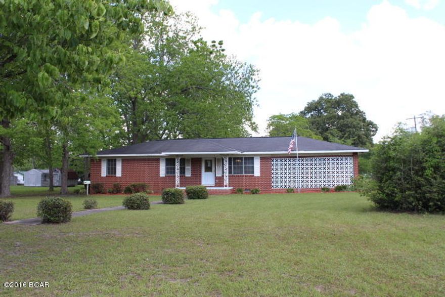 Nice brick home in town on 6 city corner lots.  House has nice features with large kitchen fully equipped and has a breakfast bar.  There is a large utility room, a screened back porch and lovely yards with nice big oak and some pecan trees. It has beautiful wood walls in kitchen, dining room and hallway  One bedroom has hardwood floors and there is carpet and wood laminate in other rooms.  There is a large yard building with electricity.