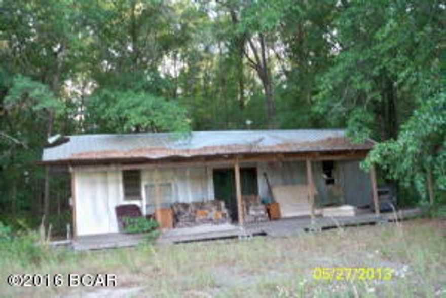 Unfinished,old, 2 bedroom hunting cabin on propety. No bath. Wood burning heater. Electric wire from barn to house is missing. Bath and water heater in barn. Septic tank on N side of barn. Barn has attached 12x40 shed and two 12x24 horse stalls. Well. Old boats and other stuff remain with the sale. Underground storm shelter. Appro 10 acs is planted in hay. Property fenced, except on the North side. 20' wide easement from property to public road. Hay field is leased for this season. BEING SOLD 'AS IS'. GET GATE KEY AT OFFICE.