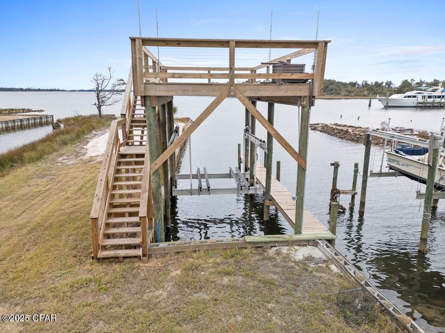 This fisherman's playground is ready for your boat! Making memories out on the water, sunbathing on the upper deck, watching Tyndall Air shows, and taking in the coasts gorgeous sunsets could be your reality with this property. It is one of the only lots along the bay that you can back your truck up to the boat dock to load and unload all of your gear (and fish!) conveniently. The lift can handle 16,000 pounds of boat with a 30 foot long dock (can be lengthened). It is currently set up for a catamaran but can be adjusted to fit most boats. This rig comes fully equipped with a fresh water wash down and motor flush. Electricity is ran to the dock for your convenience and the top deck has poles for a removable sun shade! This has all been added by the seller as well as repairing the seawall and bringing in sand to build up the area. At the front of the property there is a little fishing cabin (a 1 bed, 1 bath mobile home) that is furnished and extremely well kept. Need storage? Great! There is a shed on property as well. If you're looking for something income producing, this can be short term rented! Plenty of room for boat parking or storage and the property is partially fenced if someone wanted to gate the property in. Property is within a mile of the boat launch. Enjoy short trips to Shell Island or Panama City Beach right from your backyard! Location is everything!