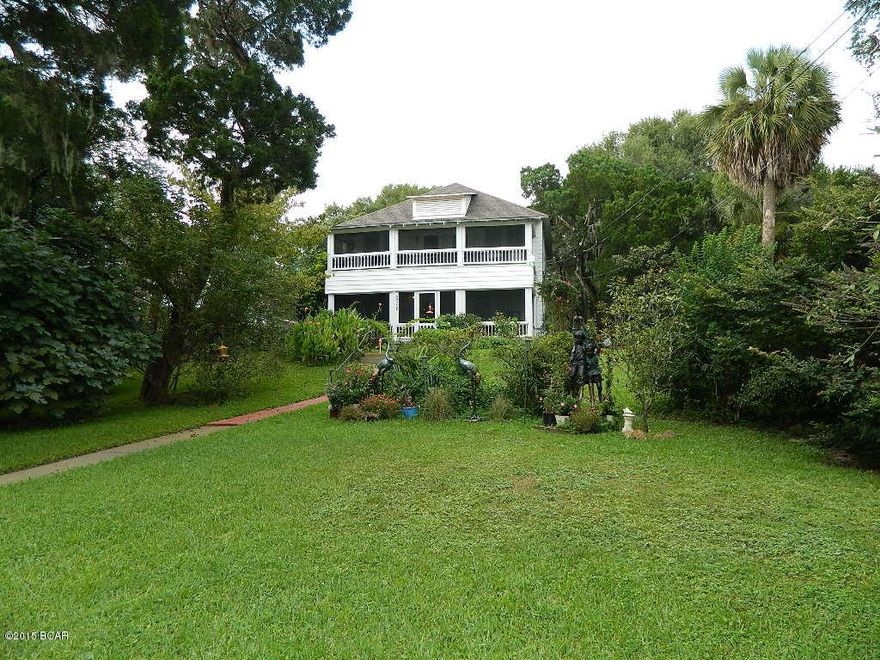 Large 2-Story Home with Bay-Front Lot for sale in Historic St. Andrews, Florida. A piece of old Florida atop a gentle rise with a breezy Bay view and it's own private beach. Four Porches. High ceilings. Fireplace. Plantation Shutters. Some original wood floors and architectural elements remain! Spacious Kitchen with butlers pantry and screen porch. On first floor there are three bedrooms with baths, office, parlor, sitting room, family room, big kitchen. On second floor are two bedroom suites each with a sitting room, bathroom, porch access. Large corner lot, small exercise pool, carport, moss filled trees. Convenient to marinas, dining, shops, parks. 15 minutes to beach. No B&B zoning.
