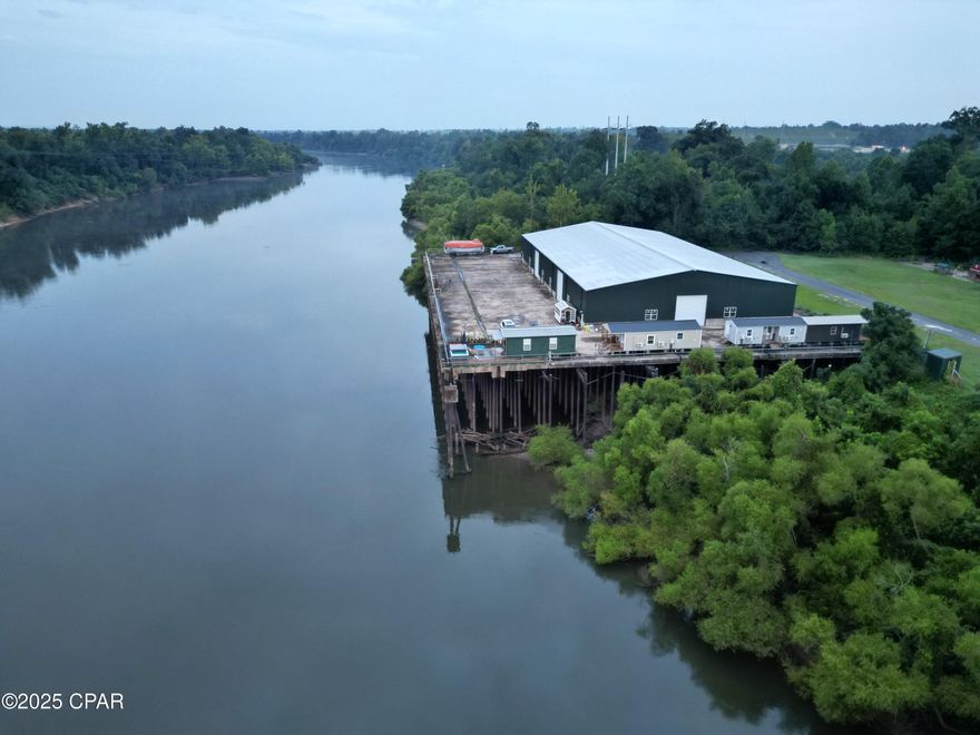 Welcome to life on the river! This premiere riverfront property presents a rare opportunity to capitalize on a prime commercial location. A 54 +/- acre gem, located in Jackson County, boasts 1,600 feet of frontage on the Apalachicola River, including over 1,100 feet of basin waterfront. Located just two miles below the Jim Woodruff Dam, the expansive acreage offers direct access to both the Apalachicola River and Lake Seminole. Renowned for its unparalleled recreational opportunities and scenic beauty, the Apalachicola River is one of North Florida's most stunning waterways and boasts exceptional diversity of freshwater fish. Anglers will find it a dream come true, catching bass, bluegill, shell cracker, crappie, channel cat, and more right from the bank! Plus, with easy boat access to the Gulf of Mexico or Lake Seminole via the Jim Woodruff Dam, a world of adventures awaits. The surrounding area teems with wildlife, including white-tail deer, turkeys, and other small game.

Enjoy panoramic river views from the property's expansive 300' x 200' concrete platform. Situated on the platform is a massive 200' x 100' metal barn with six roll-up doors. In addition to generous space for storing equipment, the building offers an ideal situation for adapting to a multitude of commercial uses.

Unleash the potential of this expansive acreage to launch your next successful commercial venture! Capitalize on the popularity of RV travel by offering guests an unforgettable riverfront experience. Five spacious outbuildings with electricity and plumbing not only provide ample storage for equipment and supplies but also present exciting possibilities for creating extra revenue streams. Envision transforming them into unique Airbnb rentals, attracting nature enthusiasts and anglers eager to explore the scenic Apalachicola River and Lake Seminole, offering them a 'glamping' experience they'll always treasure. Furthermore, the existing infrastructure creates the perfect setting for unforgettable outdoor retreats for youth groups and other large gatherings, adding additional income possibilities.

A rare opportunity awaits to acquire this stunning riverfront property brimming with both commercial potential and valuable existing amenities. Imagine the possibilities: a thriving RV park, a memorable youth retreat, or a unique residential homesite, all nestled within the heart of Northwest Florida's natural beauty. This hidden gem is more than just land; it's a key to opening a world of privacy, adventure, and recreational paradise that will draw visitors and outdoor enthusiasts from near and far. Call today to schedule a private showing and see your vision come to life!

Key features:
*Approximately half mile paved and gated entry into property off paved county road
* High recreational value
*County owned and maintained boat ramp at property entry (perfect for navigating the Apalachicola River and Lake Seminole)
*Located approximately two miles below Jim Woodruff Dam - the dam impounds 37,500 acre Lake Seminole on the common border of Florida and Georgia
* Over 1,600 feet of River frontage and 1,100 feet of basin waterfront that is sold as part of property
*Established septic and 12 inch well 
*Existing Infrastructure (enclosed 200' x 100' covered and fully enclosed concrete platform with stunning river views)
*Endless commercial opportunities
*5 Air-Conditioned Storage Buildings (30' x 14', 40' X 14', 30' X 12', 30' X 12', and 30' X 12')
*50 miles to Tallahassee, FL