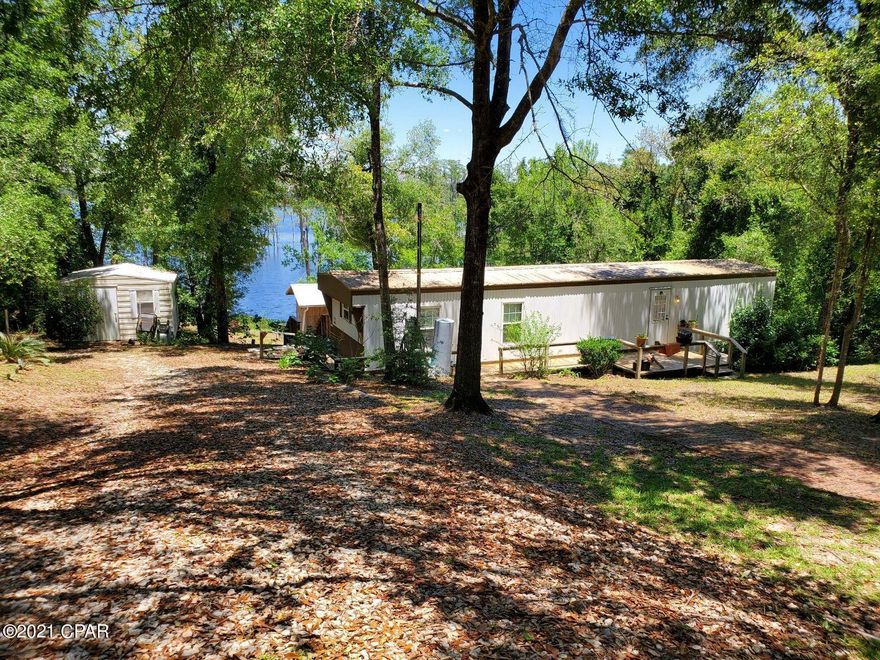 CURRENTLY UNDER CONTRACT, SELLER ACCEPTING BACKUP OFFERS. BEAUTIFUL WATERFRONT piece of land not technically in the Sunny Hills Subdivision, no HOA & not subject to deed restrictions, but basically inside Sunny Hills on Gap Lake. There's a BOATHOUSE with storage, a couple of sleeping bunks & a covered area for relaxing & entertaining near the water! Also, a shed for storage. Besides the delight of having your own waterfront property for boating, swimming & fishing, you're also near many lakes, ponds, springs, the popular Boat Lake Swimming Recreation Park, & PC Beach! Just 30 min. to the airport, 20 to Chipley, 40 to Panama City Beach & Pier Park. PLEASE NOTE: home needs flooring. BE VERY CAREFUL AND ENTER WITH CAUTION! Call for your showing today!