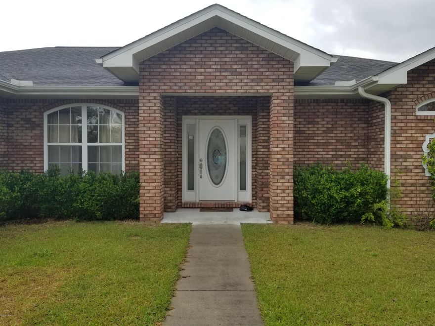 This full brick home is move in ready in Sunny Hills, not far from Panama City or the beach. It is one level and has a flat yard and features 3 bedrooms, 2 baths, 9 foot ceilings, a cathedral ceiling in the living room, with a split bedroom plan. It has a 2-car garage with extra storage above it. The kitchen is open to the dining area that is well lit with large windows, and features a breakfast bar and pantry. The laundry room is just off the kitchen and leads to the garage. One side of the house is the master bedroom and bath and has a walk-in tile shower, 2 vanities, cabinets, walk-in closet, toilet closet and tile floor. There is a door in the master bedroom that leads to the covered back patio. Come enjoy peace and quiet out in the country.