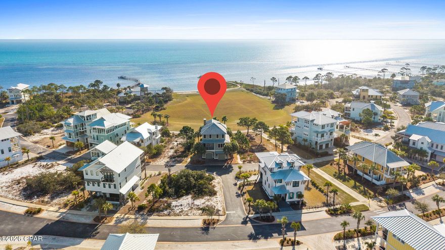 REFINED COASTAL LIVING!! Panoramic Bay views take center stage from this architecturally crafted Ovation home, perfectly positioned in the heart of the crescent across from the clubhouse. With sweeping water vistas stretching across the horizon & peek-a-boo Gulf views beyond, this home captures the very best of coastal living from the expansive decks. Morning sunrises shimmer over the Bay, while evenings bring painted skies & cool breezes that make outdoor living unforgettable. As one of the first thoughtfully designed homes built in Ovation, it set a precedent for quality construction, attention to detail & timeless architectural character within the neighborhood. From the moment you step inside, the craftsmanship is undeniable. Brazilian walnut wood floors anchor the living areas with warmth & richness, complemented by stained Andersen 8' all-wood panel doors & extensive custom molding & trim throughout. African granite counters & custom tile elevate the kitchen & baths, while a striking custom glass tile gas fireplace adds both beauty & ambiance to the main living space. Natural light pours through numerous unique windows, continuously framing those panoramic Bay views. The kitchen is designed for gathering & everyday enjoyment, featuring a gas cooktop, built-in ovens,  stainless appliances & a generous island perfect for entertaining. Two master suites provide luxurious flexibility, including a serene primary retreat with private deck access overlooking the water. The covered porches offer incredible vantage points to relax & unwind. Just steps from the clubhouse, infinity-edge bayfront pool, fire pit, fitness center, tennis & pickleball courts make this an ideal homesite. Tie up at the day dock, kayak across the Bay, fish the afternoon away, then bring your catch home to grill. Ride your bike or golf cart over to the Gulf-side pool & beach access for a sunset stroll. This is coastal living at its finest. Call for your private tour & LIVE THE BEACH LIFE!