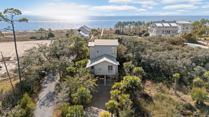 Custom-designed and thoughtfully positioned, this beachfront home on the Indian Pass peninsula offers rare privacy, elevation, and protection set back from the shoreline and surrounded by mature live oaks, palms, and pines. The setting captures true Old Florida character, perfectly paired with modern coastal architecture featuring corrugated metal and durable Hardi-plank siding, and subtle, natural color tones that blend into the landscape. Inside, the home showcases cypress wood floors, mahogany countertops, and custom windows, cabinetry, shelving, and tilework, all executed with intention and craftsmanship. First-level bedrooms feature 9-foot ceilings, while the top floor opens up to an impressive 11'8'' elevated ceiling, creating a light-filled living space that feels like a refined treehouse overlooking the Gulf. Situated on over one acre of Gulf-front property, the lot spans approximately 50 feet from Indian Pass Road to the beach, offering both accessibility and privacy. Gulf views can be enjoyed from the upper level, and a new elevated boardwalk provides an easy walk to the unspoiled, pet-friendly beaches of Indian Pass. For boating and fishing enthusiasts, a public boat ramp just down the road offers quick access to the Gulf of Mexico, Apalachicola Bay, and Indian Lagoon making this an ideal base for coastal adventures. Private, elevated, architecturally distinctive, and surrounded by natural beauty, this is a rare opportunity to own an Indian Pass beachfront retreat where Old Florida charm meets modern coastal living.