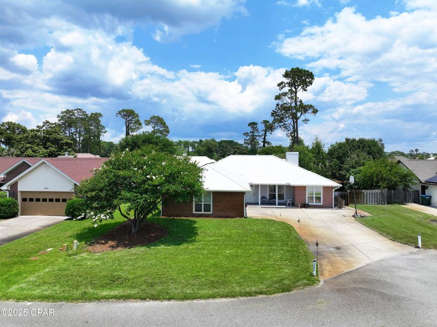 Imagine owning the perfect sized home in a super location in Grand Lagoon Shores - Even better, it is on the east end of beautiful Panama City Beach not far from several Marinas, St Andrews State Park and many well-known restaurants. Enjoy the Split plan of this one level home with 3 bedrooms, 3 baths, a sun room, an office, a kitchen, a dining room, a gym and a great big Living area. The large Master Bedroom has a huge en-suite attached.  You will enjoy two very separated vanities and separate closets with access to a tub or to a separate shower. There is a half bath and laundry room near the interior door leading to the double garage. This door also leads to the air conditioned room that served as a gym. There's more! The metal roof has solar panels that are totally paid for and will save you big bucks. The normal power bill is less than $26.  Think what you can use the extra money on- This home was built on a quarter acre lot with privacy in back.  All it needs is you to be the new owner. Short term rentals are allowed by the way, and flood insurance is not required. Welcome to your new address where there is no official HOA- just volunteer donations for the entrance upkeep.