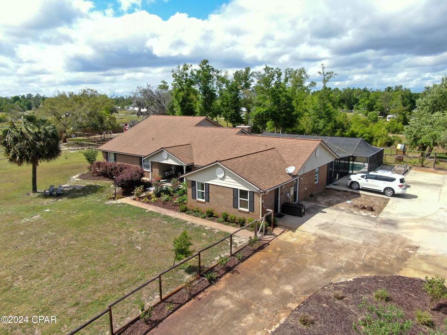 Under contract.  Seller accepting backup offers. Welcome to your serene country escape where beach meets barn. This fabulous home that sits on 2+ acres has so much to offer! The main house offers over 3800 sq ft of heated/cooled living. In addition to this, there is a unique detached garage building that offers an extra 1800 sq ft of heated/cooled area including three rooms that are separate from the large, main 2-car garage space. These rooms could be used for a variety of purposes based on your needs: a workshop, craft room, man cave, storage, home gym, or additional living space. It could also be converted to a mother-in-law suite. The HVAC in this home/garage was replaced in 2021. There is farm style fencing built around the entire parcel, and it is divided into smaller sections, perfect for creating a variety of outdoor spaces: kids play yard, dog yard, or even a hobby farm area. The front of this home is beautifully landscaped along with the lush driveway islands which you can appreciate white driving up the long, rose lined driveway. There are no less than 20 trees and shrubs planted around the property to replenish what Hurricane Michael destroyed. There are plenty of fruit trees, including mulberry, olive, bitter orange, and blueberry. Outside of the lanai, there are raised garden beds with an arched trellis perfect for growing your own fresh herbs and vegetables. The in-ground pool/hot tub is enclosed with a child-safety fence separating the pool/hot tub area from the spacious covered patio area to ensure the safety of children and pets. The pool's small waterfall creates calming background noise that only adds to the ambiance that makes this beautiful outdoor area perfect for entertaining guests year round. The master suite and closet in this home are huge, including the large master bath which boasts his and hers sinks as well as both a garden tub and luxurious glass walled shower. The master suite exits through french doors directly to the patio and pool area. In addition to the other three non-master suite bedrooms, there is a spacious bonus room that is perfect for an office/playroom or even an additional bedroom/nursery. This bonus room has an adjoining bathroom that also exits into the covered patio which is perfect while entertaining guests outside. The living room contains floor to ceiling shelving along one wall that is perfect for showing off your personal style. The stone faced, wood burning fireplace is perfect for the occasional chilly winter night in Florida. Off of the living room is a space that can be used as a playroom, home bar, formal dining room, or office. The laundry room contains plenty of cabinet storage areas as well as a sink. The eat-in kitchen/dining area is very spacious and includes wall-to-wall cabinets that double as an enormous pantry which also includes a coffee/breakfast bar, a lovely bay window, and built-in corner bench seating. With a new dishwasher (replaced last year), double ovens, a magnetic knife rack, and plentiful counter space including the large kitchen island, this gourmet kitchen is the home-chef's dream. Off of the kitchen is a side entry mudroom complete with cabinets, drawers, and countertop space that could double as an additional pantry space. Bring your Recreational Vehicles and toys! There is a 50 amp RV hookup and plenty of driveway and garage space. If you want a hobby farm, then you are set up and ready with the small barn and chicken coop located in one of the large fenced-in areas on the property! This home has a great flow to it and the versatile space can accommodate nearly any need, including multi-generational living, allowing you to turn this home into your ideal living space. It is the perfect country home in a lovely neighborhood that is within driving distance to some of the world's most beautiful beaches. (All measurements are approximate. Please verify if important.) (This home has an effective year built date of 2014.)