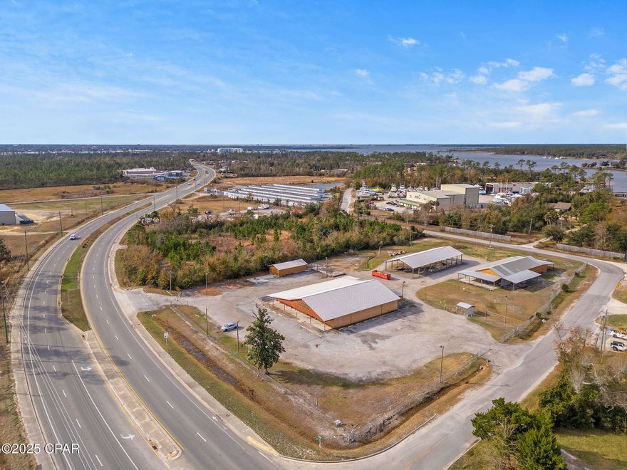 Prime commercial property on the corner of Highway 77 and Grassy Point Road in Southport, previously home to Grassy Point Hardware. This 3.21-acre property (per survey) offers versatile opportunities with multiple structures and ample space for a variety of business uses.

The main retail building features approximately 8,475 square feet of HVAC-conditioned space, 1,423 square feet of storage/workspace, and an additional 377 square feet of bonus space upstairs. The building has 10-foot ceilings and a full-width entry canopy, providing functionality and curb appeal.

Additional structures include:
•	A fully enclosed barn-style building with approximately 813 square feet.
•	Pole Barn #1: Measuring approximately 135' x 44.5', this barn includes a 6,750-square-foot concrete floor and two gravel-floor storage areas (52' x 14' and 44' x 17'). Ceiling heights range from 11.5 feet at the center to 8 feet at the sides.
•	Pole Barn #2: Approximately 108' x 40.33', featuring metal trusses, a ceiling height of 18.5 feet at the center and 13 feet at the sides, and about 60 feet of concrete flooring.

The 3.21-acre site features 295 feet of frontage on Highway 77 and approximately 700 feet along Grassy Point Road, providing excellent visibility and accessibility. Fully fenced and gated, the property ensures security and controlled access. With ample space for additional development, subject to current land use codes, it offers exceptional versatility and potential for future growth.

This property is zoned C-3 General Commercial, offering a wide range of permitted uses. Additional zoning details and information can be accessed by 'clicking' on the photo section of the property.

This site benefits from high visibility and traffic exposure, with an FDOT daily vehicle count of approximately 30,000 on Highway 77.

This excellent location is ideal for retail, storage, or commercial use, offering ample space and flexibility for a variety of business needs. Don't miss this exceptional opportunity in a growing area with prime Highway 77 frontage.
