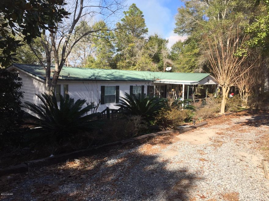 Waterfront, 155 feet on the water in the security gated community of Leisure Lakes, about 25 minutes from Lynn Haven off Hwy 77. This 3 bedroom, 2 bath mobile home with a metal roof offers nice and quiet views of the lake on two wooded lots. There is a large covered deck to watch the sunsets and a covered front porch for lounging. There are new hardwood laminate flooring in the separate dining room, living room and hallway. There is also a separate office just off the living room that has a fire place. There are two storage buildings with rollup doors, two lean-tos to store a boat, golf cart or lawn maintenance machines. A portion of the side yard is used for gardening and is fenced. Much of the property is shaded by huge oak trees.