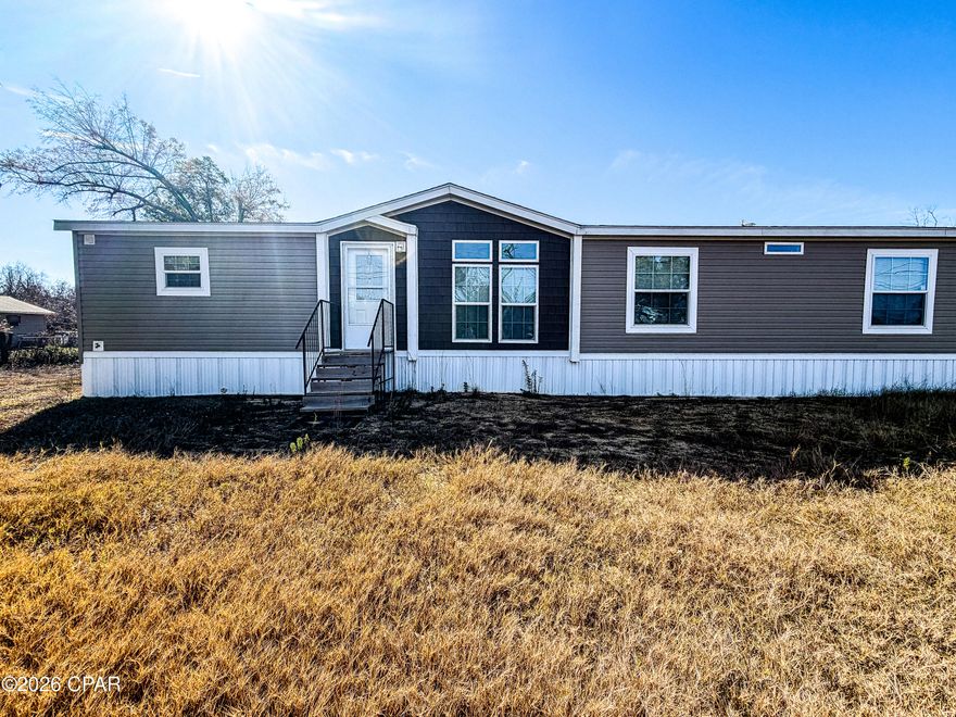 Welcome to 5036 East 14th Street, a spacious 4-bedroom, 2-bath manufactured home set on an approximately 0.95-acre lot in a peaceful area of Panama City, Florida. With plenty of room to spread out, this property offers the privacy and open space ideal for families, outdoor living, and those seeking a quieter lifestyle.

The home features an open-concept floor plan with a large kitchen offering abundant cabinet and countertop space, stainless steel appliances, and easy flow into the dining area and expansive living room. Sliding glass doors from the dining room lead to a large backyard deck—perfect for family gatherings, grilling, or enjoying the outdoors. Inside, a spacious pantry with barn doors provides excellent storage, while the living room's electric fireplace adds warmth and comfort.

The private primary suite is thoughtfully separated from the additional bedrooms and includes a walk-in closet and an en-suite bath with a separate tub and shower. Three additional bedrooms are comfortably sized and share a conveniently located guest bathroom. With nearly an acre of land to enjoy, this property offers space for children, pets, gardening, or future outdoor projects. Schedule your private showing today and experience the room to live and grow.
