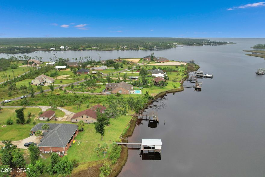 CURRENTLY UNDER CONTRACT, SELLER ACCEPTING BACKUP OFFERS. This home is a family's paradise!  The dock is minutes to the gulf, shell island and many of the local's favorite restaurants along St. Andrews Bay. The foyer of this custom home has designer tile work that leads you into the large dining room or the open family room. The open great room, bonus & master all overlook the picturesque water view. Both bedrooms downstairs have huge walk in closets. The master ensuite bath has a separate tub and spa style shower. The cozy bedrooms upstairs share a full bath. The laundry/bonus room could easily convert into another bedroom,   home gym or office. The floor plan is well designed, open  still providing room for all to find their own space. 2nd garage with AC adds more options.