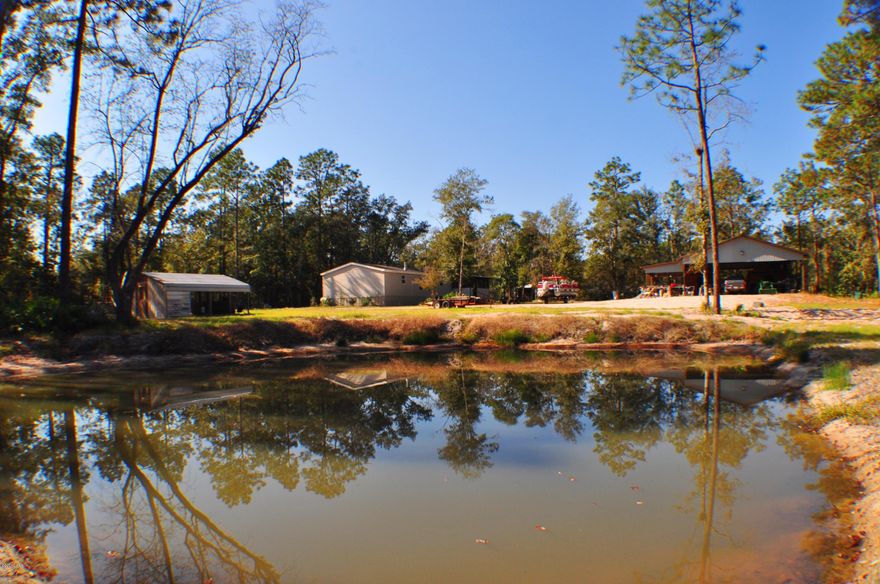 The best of both worlds! Country living with the conveniences of town less than 10 minutes away!  This 2.13 acre parcel includes a 2005 model 3BR/2BA mobile home, a large pole barn, a second out building and a private pond.  The home is approx. 1,764 sqft with a split-bedroom floor plan, fireplace, separate dining room off the kitchen and a screened porch off the back.  The pole barn has 220v power to accommodate power tools and welding equipment.  You'll love this quiet and secluded community and the property sits on a large corner lot with a circular driveway.  Come enjoy the good life!  All info is approx. and must be verified by Buyers if important.