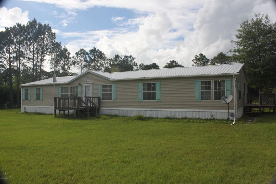 This large 4/2, 2356sf home is located off a paved drive and walking distance to a nearby park.  The property features over 2.75 acres with porches surrounding the home.  Behind the home you will find a two car garage with automatic doors, workshops and plenty of room for most anyone's needs.  A new metal roof was installed in 2014 and a new AC in 2015, a new buyer will have little worry about longevity.  The living area and den feature large rooms with a fireplace for those cold winter nights.  Your kitchen has countertops galore, much needed cabinet space and large pantry.  The master bed and bath are located on the opposite side of the home from the others, split floor plan.  The en suite has double vanities, large tub, and a separate shower with glass door and seat.  Call today!!