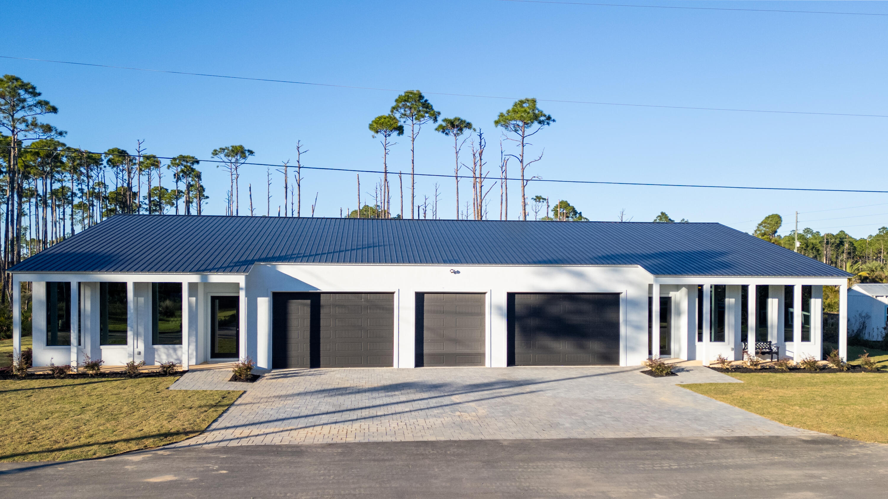 32 Delbert Lane of Santa Rosa Beach Florida is situated on .5-acres (145' x 149') in Flood Zone X, so no flood insurance is required by most mortgage lenders but is currently $560 per year. This new home is located on a private paved road, which leads to a paved bike path alongside Thompson Road to the world-class beach via Walton County public park.  This structure is built on a 7,000 square foot concrete slab, which expanse includes porches located in the front and back, has a reinforced metal roof up to accommodate solar panels. The structure was built using galvanized steel.  The windows are PPG commercial grade as are the doors.  The entire structure is rated for 170 mph winds.  This structure has two independent living areas under the one roof separated by a... 1550 square foot garage large enough for 6 vehicles ( or 3 vehicles and a 40 foot motor home with 30 amp breaker) this breaker plug can also be used for large electrical loads like an EV).  The garage doors are 10 feet high with commercial lighting in the garage.  The total conditioned space is 4480 sf. The east residence is 2,550 sf, on the west residence it is 1,850 sf. The east side contains two large bedrooms boasting 12' ceiling in one and 16' in the other. Both have a dedicated bathroom and one of the bedrooms for the master bedroom is 20' x 14'.  There is a clothes washer and dryer in the master closet and two large, beautiful barn doors originating from the 1800's.  The master bath has a free-standing tub in the wet area with the shower and a double vanity and room for a large makeup desk. The modernized commode contains smart technology.  The living room and kitchen on the east side boasts 20' ceilings, 16' dramatic tile fireplace and a very large island with a Wolf gas cooktop. The appliances are Wolf and Thermador with a Scott ice maker. The large walk-in pantry has a large wine cooler and extra refrigerator, along with countertops and plenty of storage.  The powder bath is elegant with a black toilet and a waterfall urinal that activates upon entering the bathroom.  The west residence contains 12' ceilings and a large island. Three bedrooms and two baths and laundry room. Each backyard is very large and private with room for a pool on each side. The brick-paved driveway will accommodate ~10 vehicles.  The entire structure is insulated with open cell spray foam and is efficient to heat and cool. The east residence has a 5-ton HVAC unit, and the west residence is conditioned by a 3.5-ton HVAC unit. This home was completed in late November 2024 and is ready for occupancy with the ability to rent out one or both residences for income or use one side for guests or the other side of the residence for family.