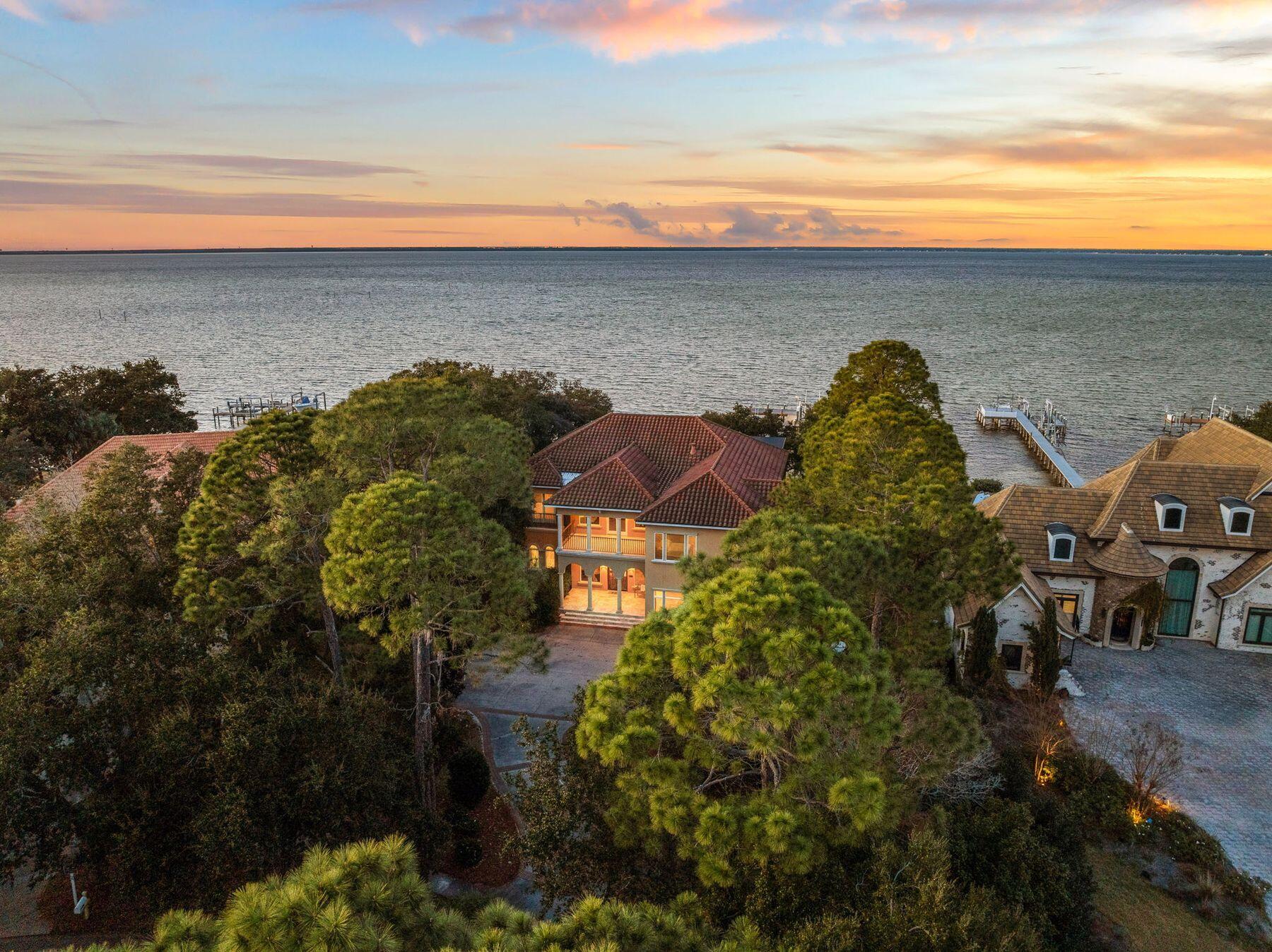 Priced to sell, this bayfront home in Kelly Plantation comes with a private boat dock, a large pool, generous outdoor entertaining space and two oversized living areas (one up and one down). The generous lot has 135 feet of prime waterfront with panoramic views across Choctawhatchee Bay. A three-car garage with arched doorways echoes the architectural style of the colonnaded front porch. Shallow steps lead up to the grand front entrance and foyer, where beautiful travertine marble flooring is laid on the diagonal, adding to the Italian ambiance. In the parlor, half-round transom windows add light to the high tray ceilings with crown molding, and a traditional fireplace adds a cozy warmth. However, the view of the pool and the bay beyond is what truly captures the attention. The master suite is in its own private wing and boasts stunning bay views to wake up to. Doors open directly to the pool. His-and-hers dressing rooms have custom built-ins. Marble continues to dominate in the luxurious master bath with two vanities and a whirlpool tub. There's also a room-sized tiled shower. The opposite side of the home has a huge great room with ample space for hosting soirees and showing off the stunning bay views. A wine refrigerator and an angled bar are perfect for serving drinks when entertaining. The kitchen has granite counters, Sub-Zero appliances, a professional gas stove and a prep sink. Custom cabinets hide an under-counter microwave, built-in refrigerator and freezer, and incorporate a professional gas range. The walk-in pantry houses even more storage and a potential wine cellar. The spacious laundry has its own shelved storage closet. A voluminous arched entrance leads to the formal dining area, which is sure to be the hub of the home for family celebrations and Thanksgiving dinners. The two-story enclosed outdoor area includes a grilling station and a koi pond, as well as the private pool. All this with a stunning backdrop of the blue bay waters. Stroll down to the dock where a boat lift and two jet ski lifts await. Back indoors, follow the wrought iron balustrade upstairs to find five bedrooms with private or Jack-and-Jill bathrooms. Generous space is evident in every room of this almost 6,000-sq.-ft. home. Luxury bathrooms, walk-in closets and bay views make this residence truly outstanding. The second-floor living room is perfect as a family room or media/entertaining room with a wet bar and mini fridge. Recent improvements include a new A/C unit (2020), new pool heater and lanai (2022), new pavers and sea wall, and a new boat dock. As well as the garage, the home has plenty of parking for up to 10 vehicles and is surrounded by dense shrubbery, ensuring privacy. The exclusive 900-acre community includes manned security gates, a golf course, clubhouse, community pool, tennis, horse stables, pickleball, a playground, and biking and walking trails. **NOTE** Photos of interior are virtually staged.