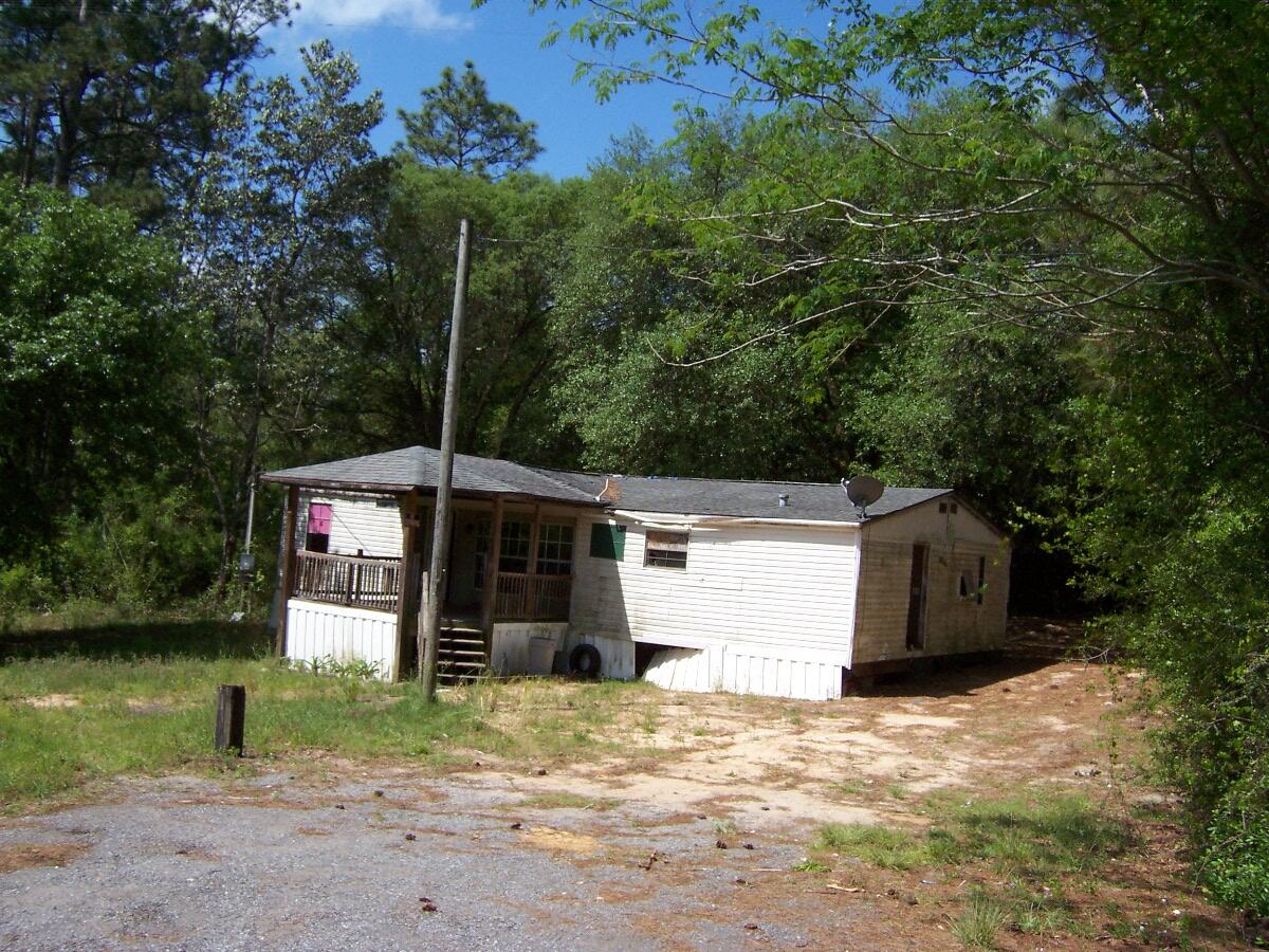 Over an acre in the county with a beautiful lot. Huge oak tree in backyard. Doublewide is in poor condition and needs extensive repairs. Property has a well (needs new pump and tank), septic and power pole. Only 15 minutes to town. Property will not qualify for traditional financing.