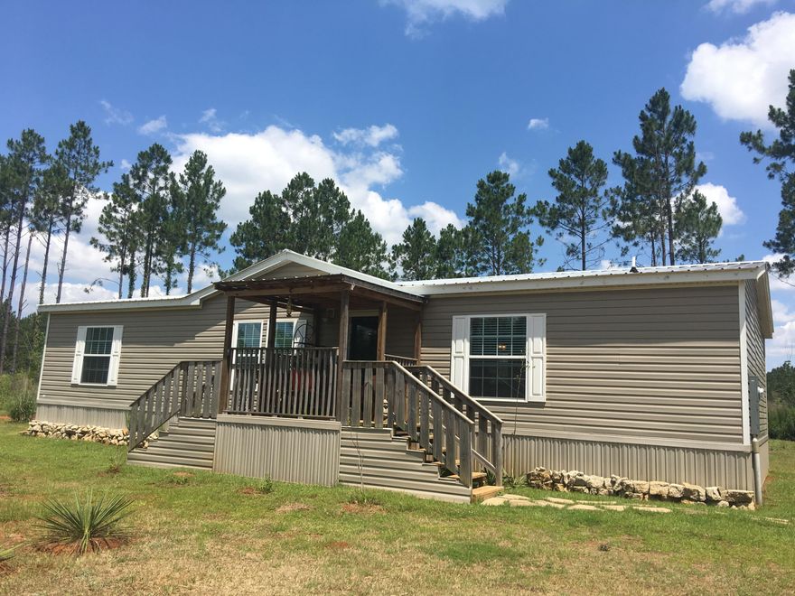 20 acres in Baker with like new mobile home. This home is top of the line with sheet rock walls, crown molding, laminated flooring, tile back splash, vinyl double pane windows, and so much more. This is a very open floor plan with an split bedroom layout. There is the possibility of two master suites with this home as two of the bedrooms have private bathrooms. The property is private and full of wildlife. You could sit on the front or back porch while watching deer graze. There is also a covered two car carport. This is a great opportunity for someone who wants to get away from it all.