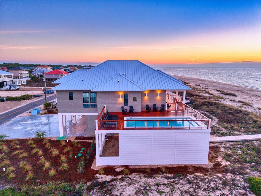 This stunning new luxurious Gulf-front home on St. George Island, with an elevated heated pool, overlooks one of America's best beaches and is being sold FULLY FURNISHED. With six bedrooms, six bathrooms, two separate living areas, elevator, pool, hot tub, and private beach access, this house was designed for large families and groups. Whether you are looking for a primary residence, second home, or investment property, this turnkey house checks all the boxes. Completed in late 2025, the ground floor heated and cooled entry foyer takes you to the main living level via an elevator. The entry foyer doubles as a game room with a pool table / ping pong table that also can serve as a dining table for the ground level. The main living level is designed for spacious group stays, featuring everything in pairs to avoid feeling crowded. You'll find two immaculate Gulf-front primary suites, each with walk-in closets and large master bathrooms. There are also two king-bed junior suites with ensuite bathrooms and Gulf views. The two remaining bedrooms also have ensuite bathrooms and share a private living space with bar area and drink refrigerator. One bedroom contains a king bed and the other contains two double beds. These bedrooms could be converted to bunk beds if additional bed space is needed. To provide separate spaces for different age groups, the home includes two distinct living areas: one overlooking the Gulf with ten-foot-tall sliding glass doors and another situated in the rear of the home. The kitchen is equipped with two French-door refrigerators, two dishwashers, a double oven, microwave drawer, ample under lighted cabinetry, and a waterfall quartz island. Laundry is made easy with two dryers and one washer. The interior d??cor is both stylish and durable, featuring quartz countertops, LVP flooring throughout, beautifully tiled bathrooms, designer lighting fixtures, a coffered ceiling in the great room, natural wood shiplap walls in the junior king suites, and sound damping accent walls in the primary suites. Natural light floods the home, complemented by abundant Gulf views from ten-foot-tall sixteen-feet-wide sliding glass doors in the living area, numerous windows, ten-foot-tall ceilings in the bedrooms, twelve-foot-tall ceilings in the living areas, and eight-foot solid-core interior doors. The layout comfortably accommodates 20 people with a matching septic capacity. The furnishings were thoughtfully curated to perfectly fit the d??cor and feature original local artwork and seriously comfortable bedding. The exterior of the home is equally impressive. An expansive, covered porch offers breathtaking views of the beach and Gulf. A large elevated heated pool connected to the house with Cumaru hardwood decking has near panoramic views of the Gulf and entire St. George Island. You must see it to understand it as words and photos cannot adequately convey the uniqueness of these views. The ground level amenities include a hot tub, beach front fire pit area, enclosed outdoor shower and restroom, private Cumaru hardwood dune walkover, and ample parking space for vehicles, boats, and RVs. There is also plenty of interior and exterior storage space to keep things organized including a ground level lockable owner's closet. The home was built to last using prestressed concrete pilings, Hardie shingle shake siding, and a standing seam metal roof. Rental projection for this exceptional property exceeds $300,000 annually.