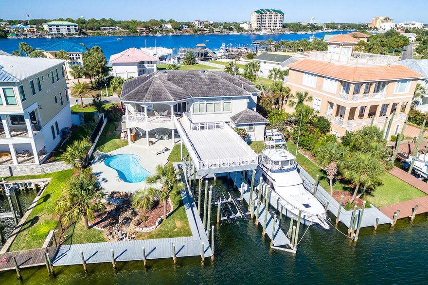 Entertainers' Dream with 2 Deep-Water Boat Slips, 2 Kitchens, and a Private Pool on Expanded Canal-Front on Holiday Isle. A 21'x51' open boat slip, and a 19'x51' covered boat slip accommodate vessels of more than 60'. The home is perched on 101' of waterfront where two canals merge allowing ease of entry, safe passage, and extended views. Travertine floors, Mediterranean-style arches, and light-filled open spaces fill the home with tastefully casual elegance. Multiple open and covered alfresco areas, an outdoor kitchen, and a large deck accessible from the second floor, allow for seamless entertaining. Indoors, a first-floor lockout with a full kitchen and living and sleeping quarters offers privacy for guests and serves as party central for poolside gatherings. Each detail of this 4,281 sq. ft. home is designed for entertaining; extras like an air-conditioned tackle room, a wine closet, and an elevator keep guests returning often. Can't miss views of the canal and the harbor highlight the second floor. Melting sunsets lead to fireworks over the harbor in this home's mile+ long views. The second-floor main kitchen offers beautiful finishes, a center island with sink, and premium appliances includes a SubZero refrigerator, a Dacor oven/microwave (installed in 2016), and a breakfast bar with seating for four. The second-floor main living area features distinctive design finishes including a coffered ceiling, Mediterranean-style columns, and a custom, built-in entertainment center. A wall of windows embraces calming water views, while sliding glass doors provide entry onto a covered veranda and large entertainers' deck with stairs leading to the canal. Beautifully appointed with travertine floors, a coffered ceiling, and a custom, built-in entertainment center, the master suite provides direct access to a covered, outdoor sitting area and the large entertainers' deck leading to the canal. An elevated, marble-inlay spa tub, sit-down shower, and separate vanities make the en suite bath a luxurious retreat. Additionally, this home features a water filtration system for the entire house, hard stucco, a flat tile roof, a 3-year-old gas water heater, an electric water heater, a 3-year-old full house generator, and two HVAC units (one installed in 2015 & the other in 2016). The grilling station provides a water line for an ice machine, and the tackle room is ready to a refrigerator or freezer for bait. Boat is also available for separate purchase: 1994 43-foot Hatteras convertible with Detroit 6V92 twin diesel engine, fully equipped fishing electronics, cabin with 2 bedrooms, kitchen, living room and bathroom. Call for a private showing of this waterfront oasis. 