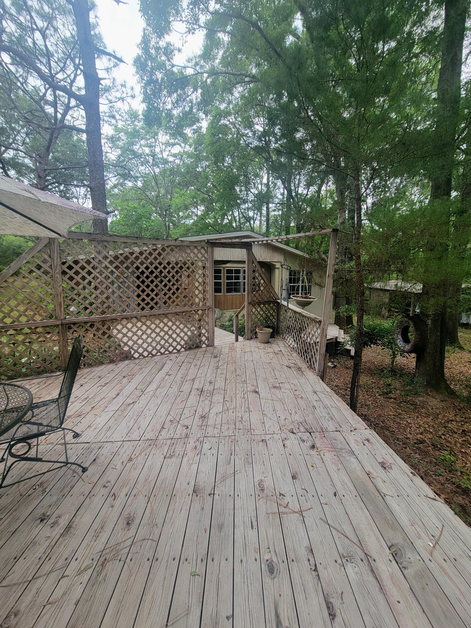 Home on 5 acres with 3 bedrooms and 2 baths with 2 bonus rooms. Central heat and air with working wood heater in den. Large kitchen with 12x6 granite top island. Large deck connected to 0x30 office. Also has portable garage metal building and a 4 stall pole barn with tack room. Many mature oak, pine and magnolia trees and partially fenced. Gum Creek passes through the property. Paved road with city water. Chelco electricity and5 adjoining acres also available. Owner financing.