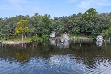 Beautifully renovated 4BR/3BA, 2,342 SF located on protected deep waters of Sarah Ann Bayou. Enjoy 50' of waterfront, seawall, deep water dock, with home located on high elevation for added peace of mind. Updates in 2019 include: Luxury vinyl plank flooring downstairs & new carpet upstairs. Remodeled bathrooms with modern finishes. Gourmet kitchen with granite countertops, tile backsplash, new cabinets, dual sink, and SS appliances. Fresh paint & select new windows. Additional upgrades include new roof (2017), updated electric panel (2013), Rinnai tankless hot water heater for energy efficiency. Spacious master suite featuring numerous closets, & luxurious en-suite bath. Relax by cozy gas fireplaces inside or entertain outside on the deck overlooking the water. Enjoy Lifestyle & Location!