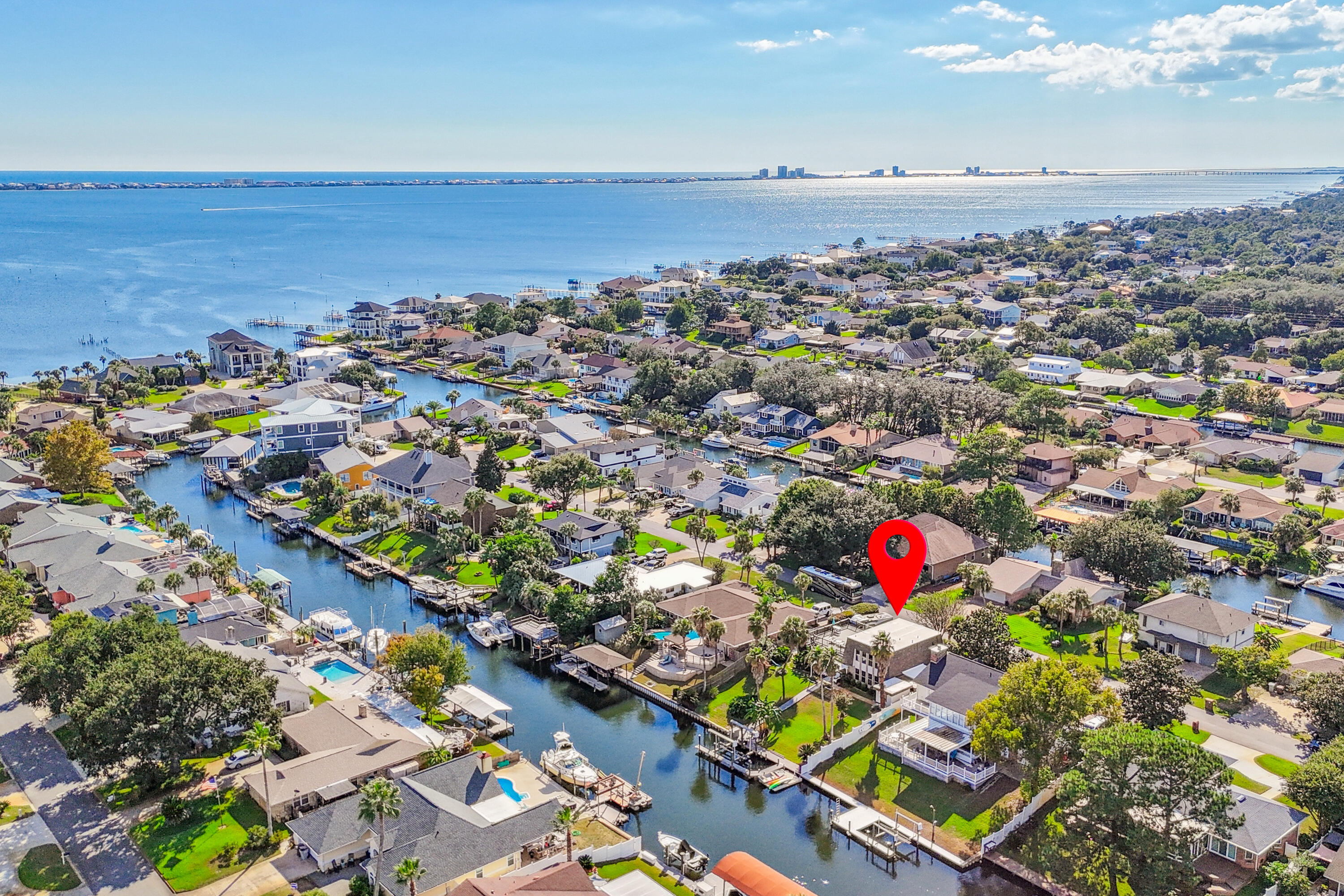 ** You are going to fall in LOVE with this absolutely stunning Canal Front home located in popular Santa Rosa Shores ** If you are an outdoorsy person, this may be your match! Nestled on a Deep Water Canal, you will find a 20,000 lb boat lift, floating dock, North Star PVC seawall, Trex decking, and more!! Tons of outdoor living space to enjoy the Florida lifestyle through all seasons ** Hosting a party? Throw it on your massive Upper Deck (783 sq ft) off the Kitchen/Dining area and overlooking the canal. The space is amazing and the views are outstanding! Want to watch the game in a shaded outdoor space? We have that too! Off the backyard  and the primary bedroom there is a cozy shaded deck area complete with a shower room great after a long day of boating ** Inside you will find all the  Inside you will find all the bedrooms on the 1st floor, with the primary bedroom overlooking the meticulously maintained yard and water ** En suite bath has been remodeled to all travertine stone, seamless glass shower doors, and radiant heated floors ** Upstairs is all the living space featuring gorgeous views, kitchen, dining area, great room and 1/2 bath ** A courtyard separates the main house from a 638 sq ft detached bonus room ** There are multiple options for this space, the current owner uses it as a game room ** Windows have a life time transferable warranty  ** 2 separate storage buildings  ** Plus this is a golf cart friendly community right around the corner from Tiger Point Golf Course and Swenson Park that has tennis, pickle ball, basketball, and playground!! Come take a look!