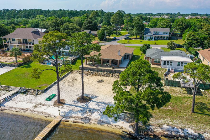 Welcome to your waterfront dream home!! This stunning property is complete with your own private beach and dock!! Step your toes into the sand of this 70' of pristine waterfront greeting you for entertaining and relaxation as you enjoy the beautiful sights and sounds of the Santa Rosa Sound. Wake in the morning and enjoy coffee from the back porch listening to the waves rolling in past the partially renovated foot path dock out to a secluded sitting area. Watch the sun rise and set from your own excusive sandy beach that makes up the rear of the property. Centrally located to shopping, schools, hospitals and entertainment, this fantastic property sits in the middle of the action yet basks in its serenity. Through the front door finds a bright foyer open to the dining and living areas of the home complete
with a view of the sound through the glass doors at the end of the living area. To the left of the foyer will
be the two guest rooms and guest restroom. The kitchen to the right features a brand new oven and
matching dishwasher. The spacious two car garage will house vehicles, goft carts and/or provide ample
storage.
The large owners suite also boosts gorgeous views and sounds of this waterfront retreat. Step out onto
the covered porch and enjoy the gorgeous water views. Closet space and storage cap off this 2153 sq ft beauty.