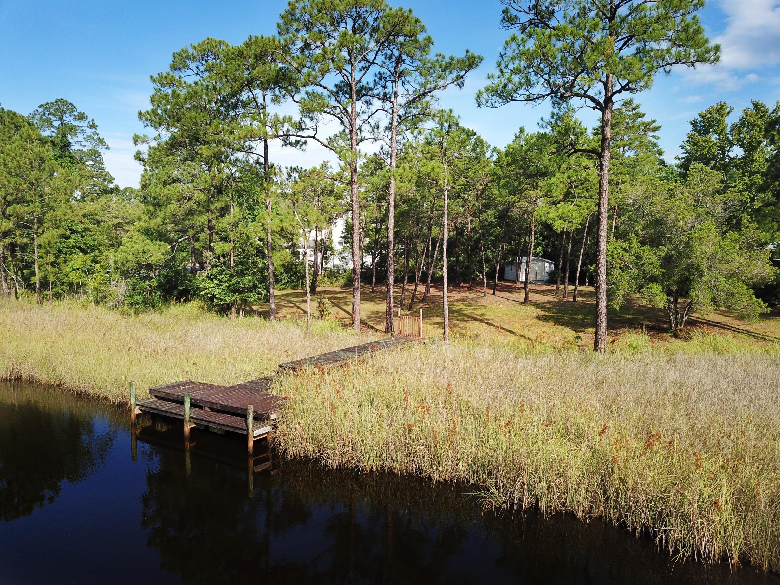 Southern facing WATERFRONT lot with dock on 170 ft of waterfront, overlooking McQuage Bayou in Pt Washington, with access to the Bay. Build one large waterfront home with commanding views and privacy and have ample yard, or hold without building. No buildout times, no hoa, no dues. Beautiful views across the bayou. Why buy on 30A when you can retreat to waterfront living at a fraction of the price and drive 4 miles to Grayton Beach, WaterColor and Seaside. Mostly state forest along the way. Must act quickly!