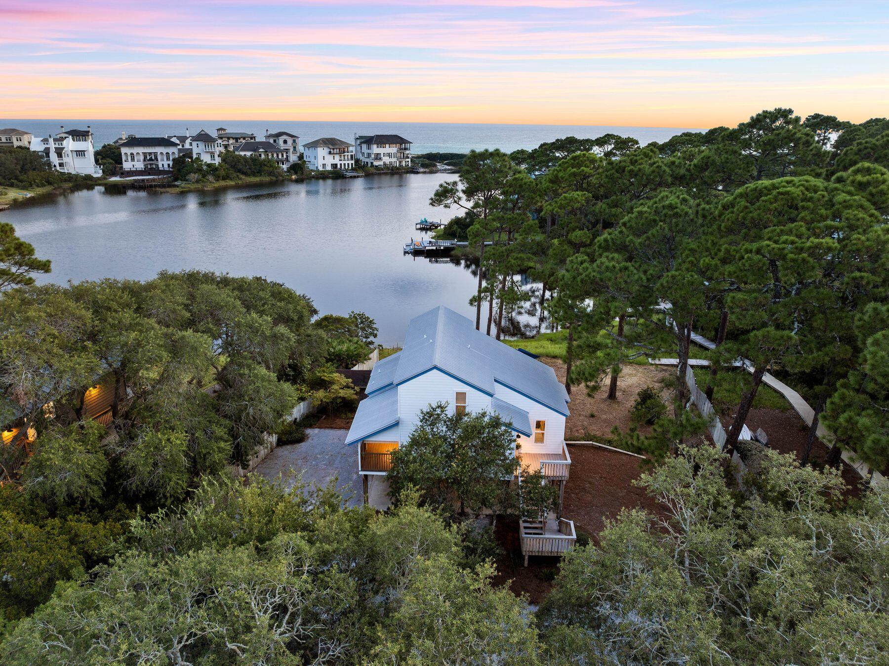 This updated waterfront beach house presents a rare opportunity to enjoy lakefront living with amazing gulf views and watersports access. Mature landscaping provides seclusion and privacy along with 100 feet of pristine water frontage on Stallworth Lake. A boardwalk leads down to the water's edge, where the new dock is perfect for fishing or launching paddleboards and kayaks. This rare coastal dune lake provides direct access to the Gulf of Mexico for swimming and beach days. Recently restored to a high standard, this elevated home has a contemporary vibe with new LVP flooring, bathrooms, lighting, and high-end coastal-inspired furnishings.