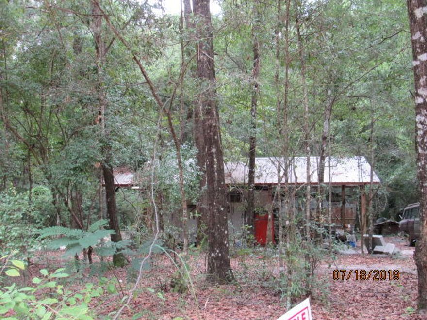 7.5 acres in country setting within 2 miles of Ponce de Leon. Fronts county maintained dirt road. Property is being sold AS IS. Seller is not removing any items. There are a couple very old campers of no value and some junk cars. There are three pole barns on land, and a portable building is located under barn. There is a deep well & power pole, but no septic. It is estimated that half of land is low lying. Clean up this property and build your home, or park your camper under one of the barns. No restrictions. The land is wooded.