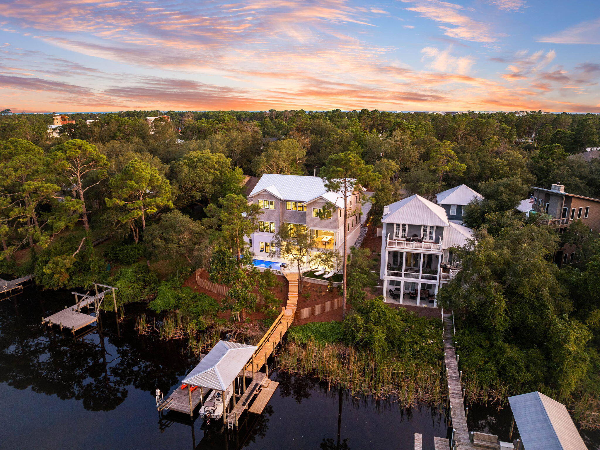 Experience the best of both beach and lake lifestyles at 802 N Walton Lake Shore, Inlet Beach, FL. Discover unparalleled coastal luxury in this stunning new construction by Focus Construction, offering an unmatched lifestyle experience on Lake Powell. This custom home spans 6,047 sq. ft., featuring five bedrooms and 5.5 baths, offering ample space for family and guests.As you enter the home, you are greeted by an inviting foyer with pecky cypress accent ceilings and Venetian plaster accent walls. The main level seamlessly flows into an expansive family room, dining area, and gourmet kitchen. The kitchen is a chef's dream, equipped with premium Wolf/Sub-Zero, and Cove appliances, a large island with a waterfall edge, and abundant storage space. The main family room overlooks the serene waters of Lake Powell, perfect for enjoying sunsets. The outdoor BBQ and dining area on Ipe decking are located on the main floor covered porch off the kitchen.

The primary suite on the main floor offers stunning water views, a spacious walk-in closet with custom built-in shelving, and a spa-like bathroom featuring floating vanities, under-cabinet lighting, and high-end fixtures. This level also includes a powder room and a mudroom/laundry area adjacent to the two-car garage.

Descend to the lower level, where you will find an additional bedroom with an en-suite bathroom and generous walk-in closet. The entertainment options are endless, with a movie theater room outfitted with Sonos sound, a wine room with a wet bar, and an in-home gym. The lower level opens to the outdoor living area, where you can relax in the heated pool and hot tub with laminar pool deck jets, and enjoy the peacock paver pool deck.

The second floor features three more bedrooms, each with an en-suite bathroom and walk-in closet. An additional living room/recreation room offers a perfect space for relaxation and entertainment. Large windows throughout the home fill the interior spaces with natural light, enhancing the coastal ambiance.

Outdoor living is at its finest, with direct access to Lake Powell from your private dock, which includes a boat house, and boat lift, perfect for boating on the lake. Proximity to 30A Avenue ensures easy access to renowned dining options like Amigos and Amici 30A, Cuvee 30A, Idyll Hounds Proper, The Donut Hole, and Aja Elevated Asian Kitchen, along with shopping destinations. Enjoy easy access to the white sandy Gulf of Mexico beaches and Rosemary Beach through the new pedestrian underpass.

This home is built with modern conveniences in mind, featuring Eurowall sliding doors, custom hand-fabricated railings, extensive storage options, cedar shake siding, galvanized half-round gutters, outdoor gas lanterns, and landscape lighting. The interior is further enhanced with custom Marquis Fine Cabinetry.

Take advantage of the opportunity to live the best of both beach and lake lifestyles in this breathtaking home. Schedule your private tour today and experience the luxury and elegance of 802 N Walton Lake Shore.
