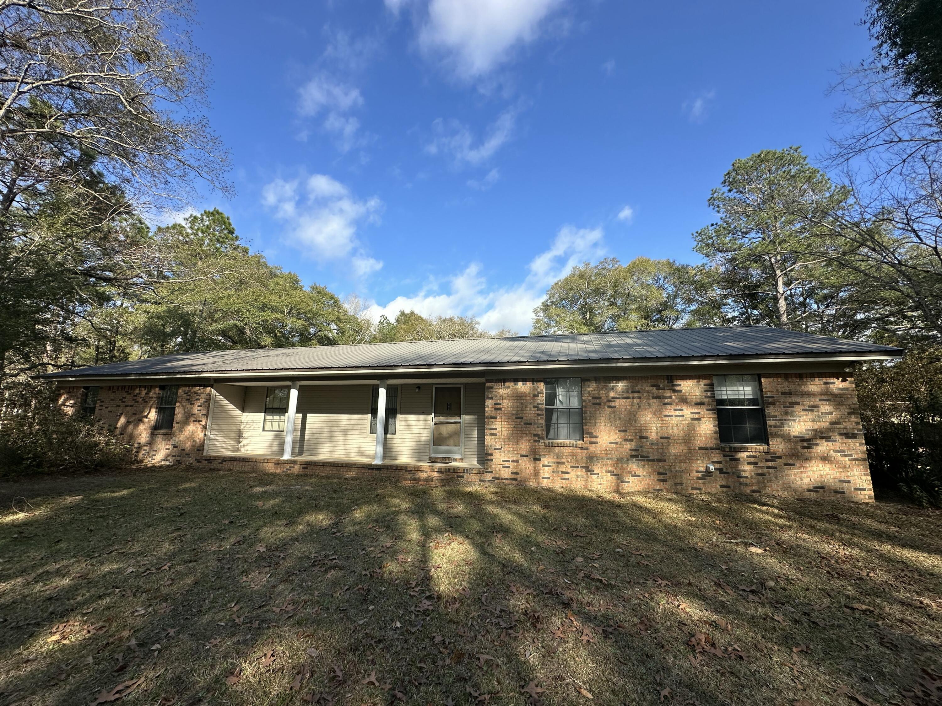Experience the perfect harmony of comfort and nature at this delightful property. A solid, all-brick home with a durable metal roof rests on two serene acres, graced by magnificent oak trees. Picture cozy evenings warmed by the woodburning stove, and peaceful mornings on the back porch, where the gentle sounds of birdsong and rustling oak leaves create a truly immersive natural retreat. This is more than just a home; it's a private escape, a place where the beauty of nature and the comforts of home blend seamlessly. Zoning is rural residential