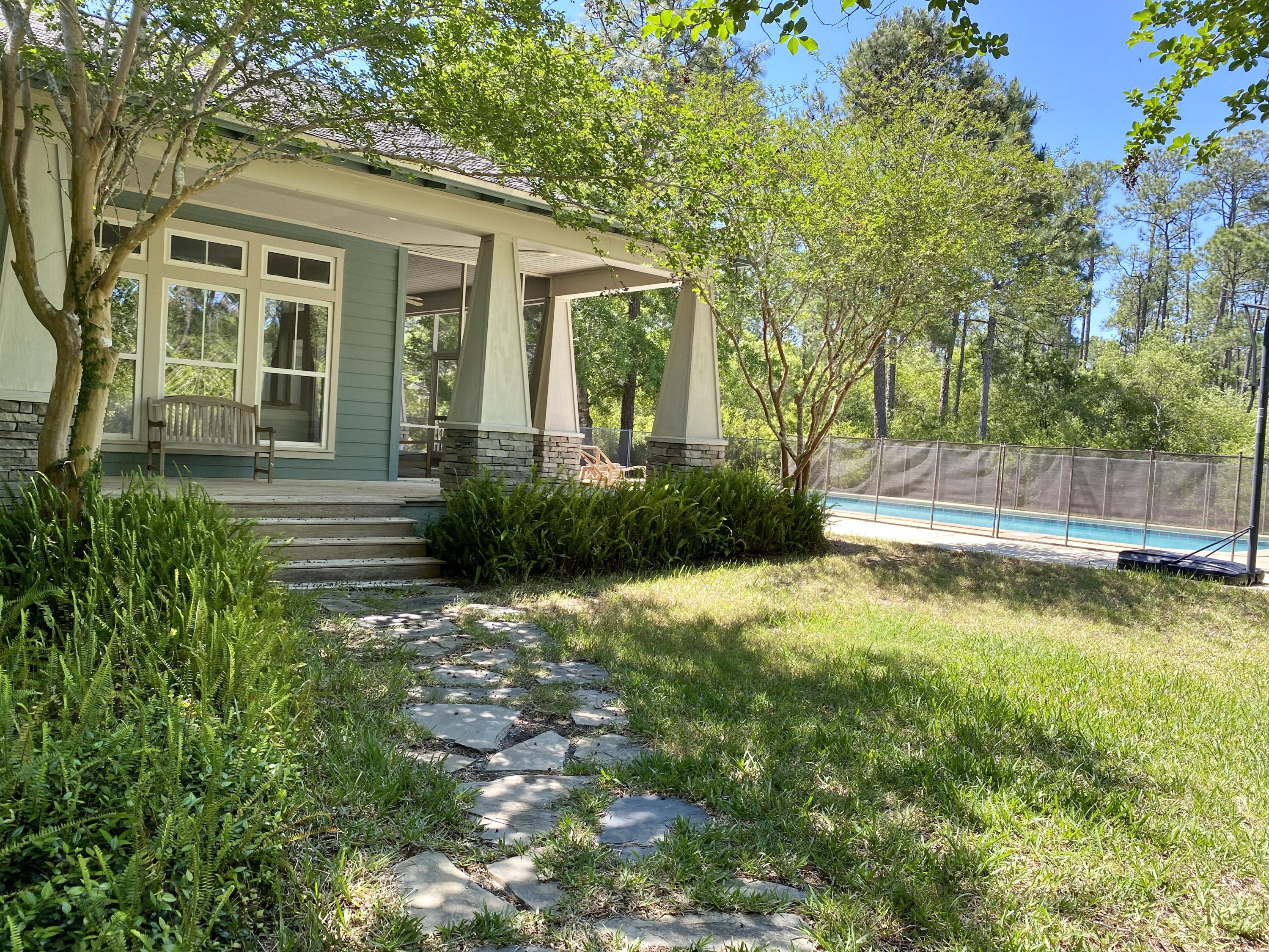 This storybook craftsman style home is nestled on a large lot at the end of a cul-de-sac in The Woods subdivision of Point Washington. Charm greets you the moment you walk through the picket gate into a lovely yard and step onto the inviting large front porch adorned with stone columns. Private entry into the fully enclosed breezeway between the garage and front door. The home is bright and light with an open concept kitchen, dining, and living space. The spacious kitchen features gas cooktop, breakfast bar and plenty of cabinet space. The large living room is centered by a stone fireplace, surrounded by quiet natural light and opens to the screened porch providing a flowing living space extending outdoors. Master bedroom off the living room with the other side of the dual sided fireplace.