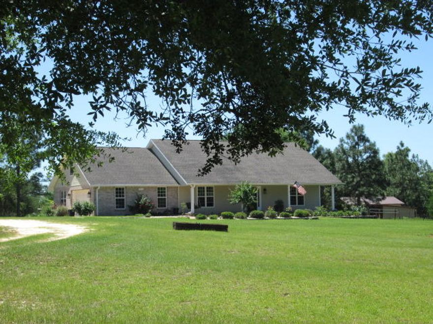 You will be amazed at the gorgeous sight that awaits you at the end of the long driveway. Acres of beautifully landscaped property surrounds this amazing five bedroom custom home. Home is built with ICF(Insulated Concrete Forms) which is designed to withstand a 200 MPH wind load and has an R50 insulation rating!! The wide front porch is the perfect place to sit and enjoy the expansive, professionally maintained front yard. Entering the home you'll notice the lovely neutral colored walls and tile flooring. The living room is enhanced by the corner gas fireplace. The chef will love the gourmet kitchen with custom Hickory wood cabinets, Corian counter tops, under cabinet lighting, stainless steel appliances, gas stove top and hop -up eating bar. Breakfast nook overlooks the back yard