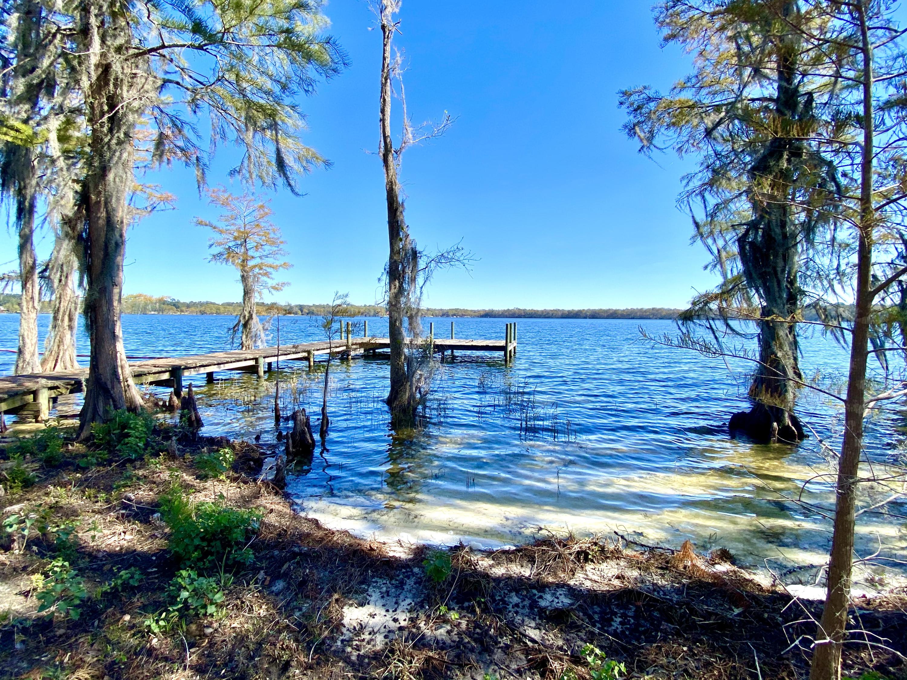 RARE OPPORTUNITY! Gated waterfront community directly on HISTORIC LAKE JACKSON, the largest natural lake in the State of Alabama, only 18 minute stroll from Crestview, right off HWY 85! This AMAZING .37 acre flat building lot has 96 ft of water frontage and is ready to build your lake house! Have your own sandy beach and boat dock nestled amongst the beautiful cypress trees. The position of this lot offers the widest view of the lake, and lots like these often pass through families for generations and never hit the market. There is a dock currently in place, although the top boards are in need of replacement/repair. You can literally walk across the state line into Florida from this property, but benefit from lower Alabama taxes. There are covenants and restrictions in place and
