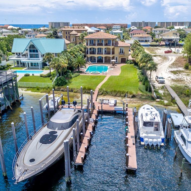 Find your safe harbor with this dream estate located directly on Destin's beautiful harbor! The fabulous large lot boasts a 3-story Mediterranean-style masterpiece, an expansive patio, enormous pool, and phenomenal boat dock configuration. Extensive site work with retaining walls provides favorable lot elevation, so that the home enjoys a nice perch with views in all directions. The amazing boat dock, which has received significant upgrades, includes 4 areas in which to moor vessels: one that will accommodate a boat perhaps as long as 90', a 50,000-lb boat lift, 5,000-lb boat lift, jet ski lift, and much more--a yachtman's paradise!The same careful attention was committed to the craftsmanship of the interior. Easily accessed via elevator, the residence's