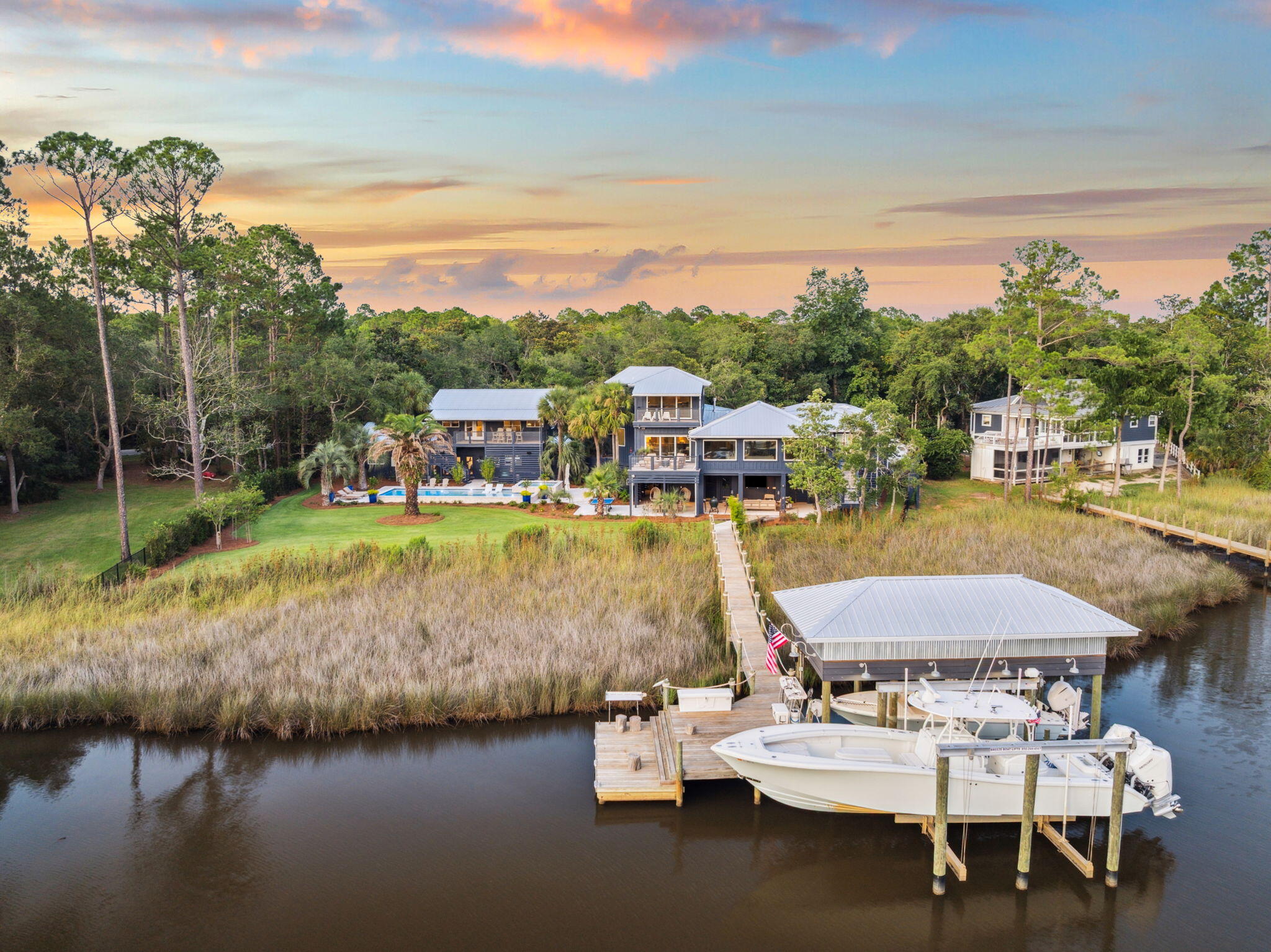 Welcome to this stunning waterfront retreat in historic Point Washington!Facing Tucker Bayou, this 5,000+ Sq Ft family compound offers the best of Bay front living. The main house features an open floor plan, perfect for entertaining with water views from every angle. You can enjoy cozy gatherings around the dining peninsula in the kitchen or step onto the open deck to relax by the fire with a sunset view. The waterfront primary suite provides a serene retreat with private deck access, a sitting area, large walk-in closets, and a spa bath with a soaking tub and separate shower. Three additional bedrooms with bathrooms are located in the main house, complete with a private den for movie nights and a half bath. Upstairs, a versatile multipurpose room offers space for lounging, working, and waterfront viewing from the covered deck.
The outdoor entertainment area is the epitome of outdoor living. Here, you can enjoy a game of ping pong or take a refreshing dip in the pool before settling into the lounge area. This space is perfect for tending to the grill and enjoying seated dining for ten.
For those who love being on the water, a private two-slip dock is just down the boardwalk. From here, you can embark on a spin around the Choctawhatchee Bay or a short boat ride to dinner at The Bay, North Beach Social, or Farm & Fire.
Above the conditioned two-car garage are private guest quarters with two bedrooms, a full bath, laundry facilities, a well-appointed kitchen, and a spacious living room with a covered deck overlooking the pool and Tucker Bayou. The conveniences of home continue with a private gym, sauna with a full bath, and an enclosed covered storage area.
Several design appointments featured in the home include washed Pecky Cypress, nickel gap planked walls, 12" wide saw-cut reclaimed oak floors, two laundry rooms, a Butler's Pantry, antique rugs, beautiful furnishings, unique wallpaper, a heated saltwater pool with sun shelf and raised spa, modern stainless exterior railings, four additional covered parking spaces, landscape lighting, a well irrigation system, and Ipe decking.Enjoy the thoughtfully designed native gardening and landscaping among the stunning Live Oak trees, palms, palmettos, and magnolias. All this is within minutes of the Beaches of 30A, shops, restaurants, schools, and Eden State Park.