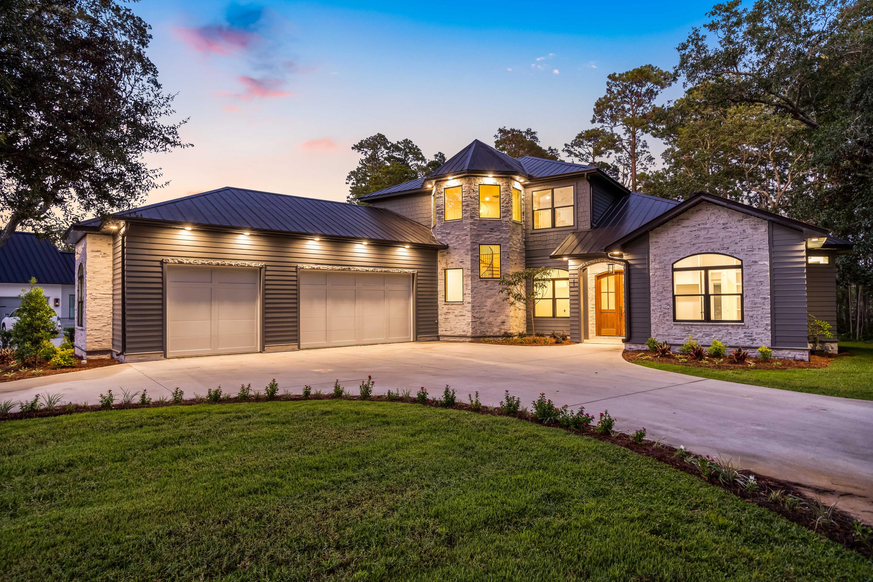 Introducing 180 Grand Flora Way, a brand new waterfront residence in the prestigious Botany Bay Subdivision of Santa Rosa Beach, Florida. The 5-bedroom home offers 3,657sf of living with over 5000sf under roof including the garage and the outdoor patio area. Inside the gates of Botany Bayou you'll find a mature neighborhood of local renown with majestic oaks lingering endlessly. Upon arrival step through the custom Mahogany French doors adorned with brass Emtek handle set and be greeted by the warm glow of a gas lantern, a preview of the elegance that lies within. As you enter, you'll be embraced by the timeless beauty of engineered hardwood flooring that stretches throughout the home, creating a seamless flow from room to room.