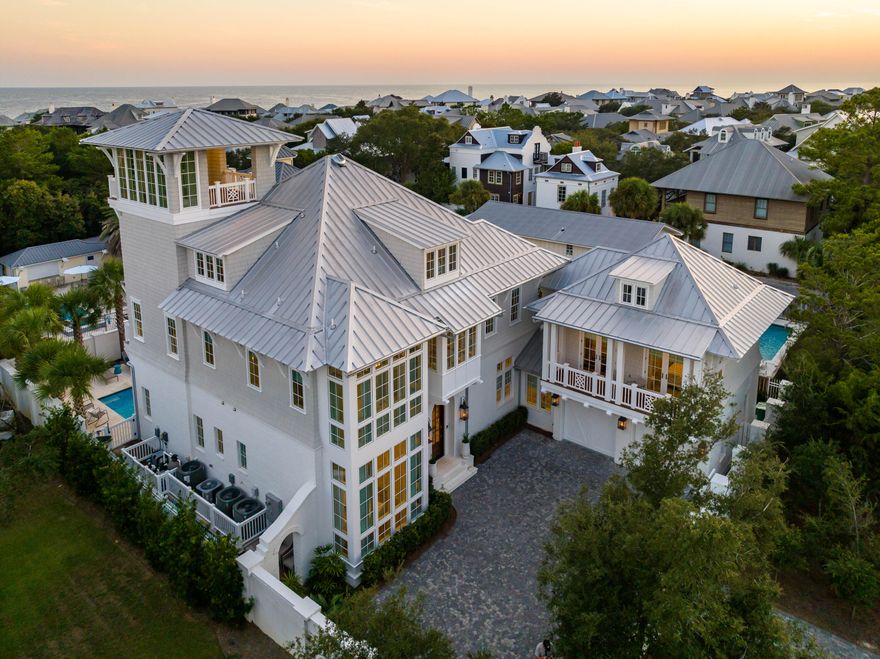 Experience elite coastal living expertly curated for a life of everyday indulgence. This timeless gulf side estate offers a five-bedroom primary home, one-bedroom carriage home atop the two-car garage, gated entry, elevator, gulf view tower, and a brick-walled courtyard with private pool perfectly positioned only steps from the Gulf of Mexico and the quaint streets of Rosemary Beach. Revel in unmatched privacy concealed behind elegant brick walls, cocooning you in a world of pure coastal splendor. From the moment of entry through the curved 10' wood door, the expert level of construction employed throughout the property built in 2020 is immediately evident with a grand foyer featuring a stunning staircase with twisting balusters, Venetian plaster curved walls, intricate millwork and a beautiful custom chandelier. Continue ahead to the expansive living and dining space with shiplap wrapped walls and ceilings contrasting with white oak hardwood floors and natural ceiling beams. At the heart of the living area, a gas masonry fireplace features custom built-ins to each side. A wall of windows with welcoming sunlight streaming in overlooks the masterfully manicured pool area. The stunningly appointed kitchen features all of the accoutrements desired by a chef of the highest skill including premium Wolf and Sub-Zero appliances including a wood wrapped vent hood and six-burner stove, quartz countertops, floor-to-ceiling custom cabinetry, and a showpiece geometric backsplash from counter to ceiling. Both a separate wet bar with wine refrigerator and icemaker and a butler's pantry with dishwasher and sink allow for effortless entertaining.
Accessed directly from the living space, enchanting outdoor spaces await including a covered living and dining room with a tabby shell fireplace, full summer kitchen with grill, vent hood, refrigerator, icemaker, and sink, and both a powder bath and separate shower. The heated saltwater pool features a sun shelf and mature palms lining the peacock paver patio. An easy maintenance turf yard leads around the house past intricately placed foliage including mature oleanders, crepe myrtles, Japanese yew, succulents, and lush flowering pots to an Ipe deck with gas firepit and Adirondack chairs. The courtyard fully surrounds the property adding both security and privacy to the home along with a magical feel of having your own private garden amidst one of the most coveted areas of 30A.
Additional features of the first level of the home include a junior master suite with a wall of windows overlooking Scenic Highway 30A, shiplap ceilings, custom draperies, and a luxurious ensuite with a marble tiled walk-in shower, inset cabinets, and a dual vanity with a gorgeous mosaic tiled wall behind. A powder bath is also located off the foyer for guests. The mud room with built-in lockers and brick floors, and one of two laundry rooms areas is positioned off the kitchen providing access to both the two-car garage with epoxy flooring and the carriage home. The carriage home offers spaces finished as exquisitely as the primary home with a large kitchen with full-size appliances and farmhouse sink, shiplap ceilings in the living area, bathroom, and bedroom large enough to accommodate a king bed with a private balcony.
Ascend the curved staircase or take the elevator to the second level of the home to find the grand primary master suite offering a private balcony overlooking the pool courtyard. With coffered shiplap ceilings and an arched doorway leading to a separate sitting area complete with retractable TV and morning bar with espresso machine, sink, and refrigerator, this suite is truly a serene retreat from the world. The luxurious ensuite is incredibly spacious with a closet with built-in storage, an expansive vanity with additional built-in storage, a walk-in marble shower, and a separate soaking tub beneath a custom chandelier. Two additional guest suites, equally lovely, with private ensuites are also located on the second level along with a built-in storage bench overlooking Scenic Highway 30A and a tiled laundry room.
The third floor offers a comfortable secondary living space, a shiplap wrapped bunk room with custom built-in bunks for four, and a full bathroom. A bar area services this space with a refrigerator, icemaker, and sink making it a complete entertaining space. From this level, stairs lead to the 4th floor tower soaring high over the Rosemary Beach and Inlet Beach communities with spectacular 180-degree gulf views. This large, covered space is outfitted with a ceiling sound system and TV power hook-up. Create the ultimate open-air haven for cozy evenings spent savoring the sunset.
An unequivocally unique opportunity, this gated estate is offered fully furnished with designer appointments including art. Owners can enjoy an unparalleled location only a one-minute walk from the beach and the shopping, dining, and activities of both Rosemary Beach and Inlet Beach yet not constrained by HOAs or private community guidelines. Built to the highest standards, this private retreat allows for an exceptional life curated with true artistry.