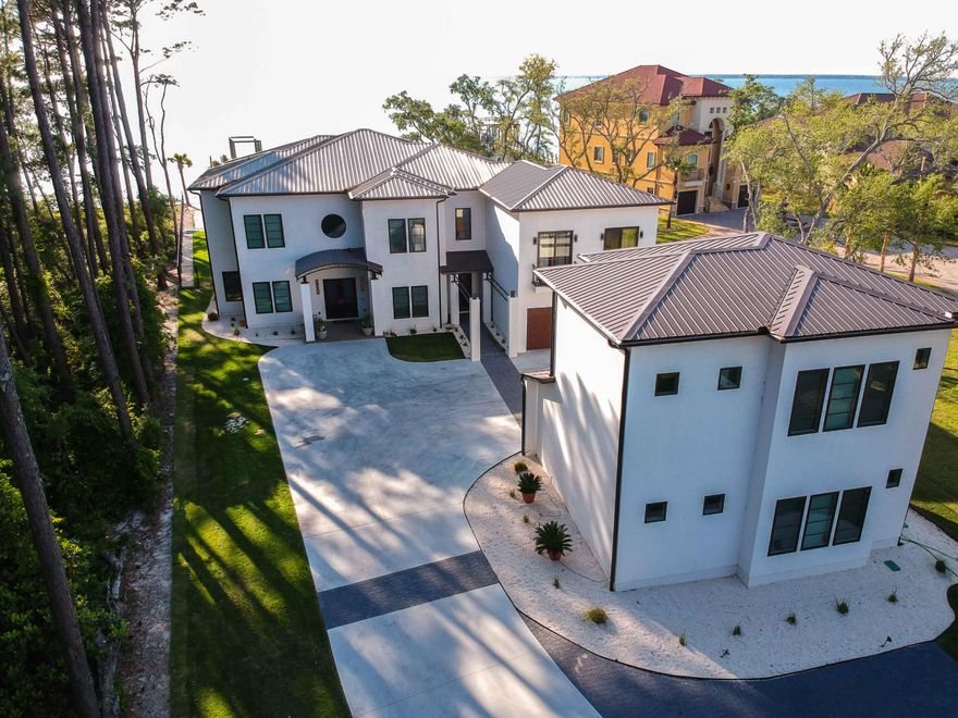 ONE OF A KIND! There is truly nothing else like this on the market! This contemporary and magnificent 6170 sq ft private gated bayfront estate is located only 7 minutes from World-Class dining and shopping at Grand Boulevard. Enjoy boating in the Choctawhatchee Bay, golfing in nearby Sandestin and the whitest beaches in the world on 30A.Upon entering the property, the long palm tree lined driveway and meticulously groomed landscape greet you as you approach this modern contemporary newly built 2017 custom home. Featuring a four-bay garage and a well-appointed 2-bedroom carriage house, this home is situated on a 1 acre lot that has been elevated to 8 feet above sea level. It boasts 120 feet of prime water frontage and the property has its' own private beach!