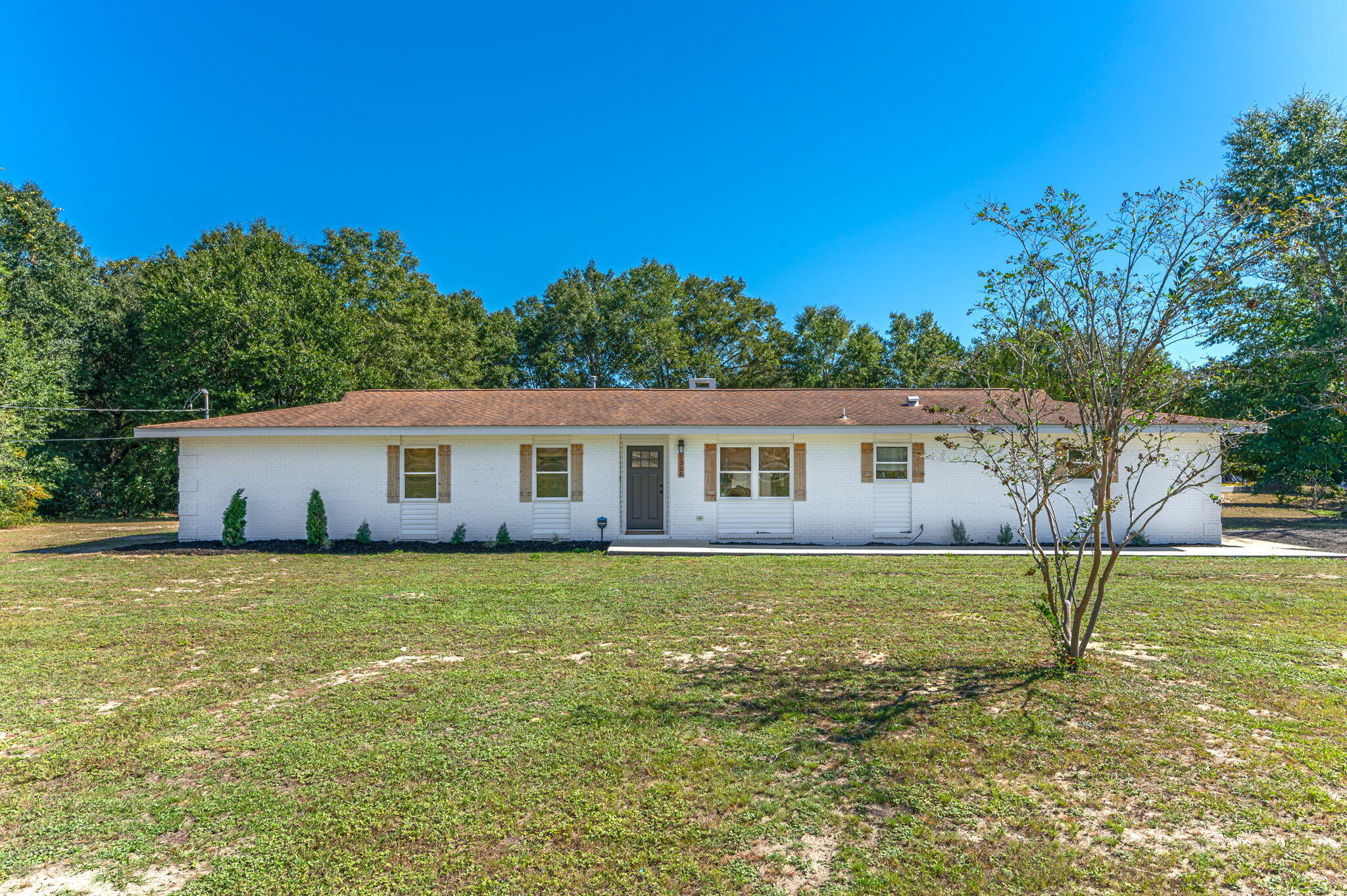 Welcome to 1306 Grandview Dr, a beautifully renovated home on a peaceful 1-acre lot in Crestview, FL. This home offers modern updates with classic charm, perfect for comfortable living.  A bright living room with luxury vinyl plank flooring, recessed lighting, and a cozy fireplace flows into the dining area and kitchen, creating an inviting space for entertaining. The gourmet kitchen features marble countertops, stainless steel appliances, white shaker cabinets, and a spacious island with bar seating.Three spacious bedrooms with ample natural light. The master suite includes an updated en-suite bath with a walk-in shower. Both bathrooms feature modern vanities and fixtures. The large backyard is perfect for gatherings or relaxation, with a patio ready for outdoor dining.