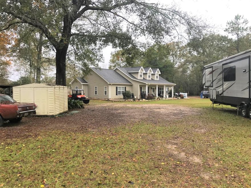 As you enter the property you will see this beautiful house with it's gable roof and dormers. Large cement porch the length of the home. Entering the house there's a large 5.6 x 17.8 foot foyer. The living room is to the end on the right and kitchen and dining room are to you left. Beyond the kitchen is the laundry room with a door to the porch out back. The master bedroom is to your left. It's large with a generous sitting room. And And a large master bathroom with a walk in shower and separate tub. On the other side of the house are the additional 3 bedrooms with two of them sharing a Jack 'n Jill bath. Out back you can enjoy the lengthy porch that goes all the distance of the house. You walk in the back yard and there are so many bushes and trees. golf cart trails all through the woods, there's a big pond out back..  Plus you'll have a 30x40' metal shop with 200 amp service.  There's also 2 septic tanks on the property and several RV hook ups.  The house has a metal roof and the yard is beautifully landscaped with statues and fountains. The home and shop both have solar.  This is a wonderful place to call home! 